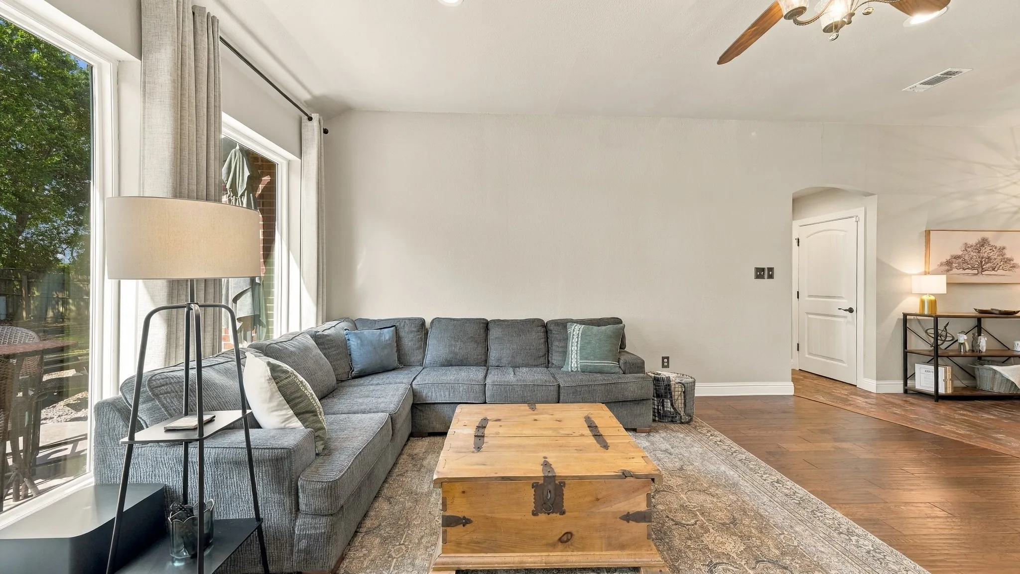 Recessed lighting, wood-finish flooring, a ceiling fan, and large windows with privacy drapes