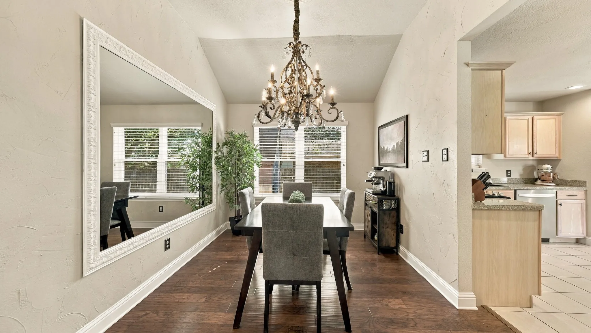 Vaulted ceiling with an ornate chandelier, wood-finish flooring, and white baseboards