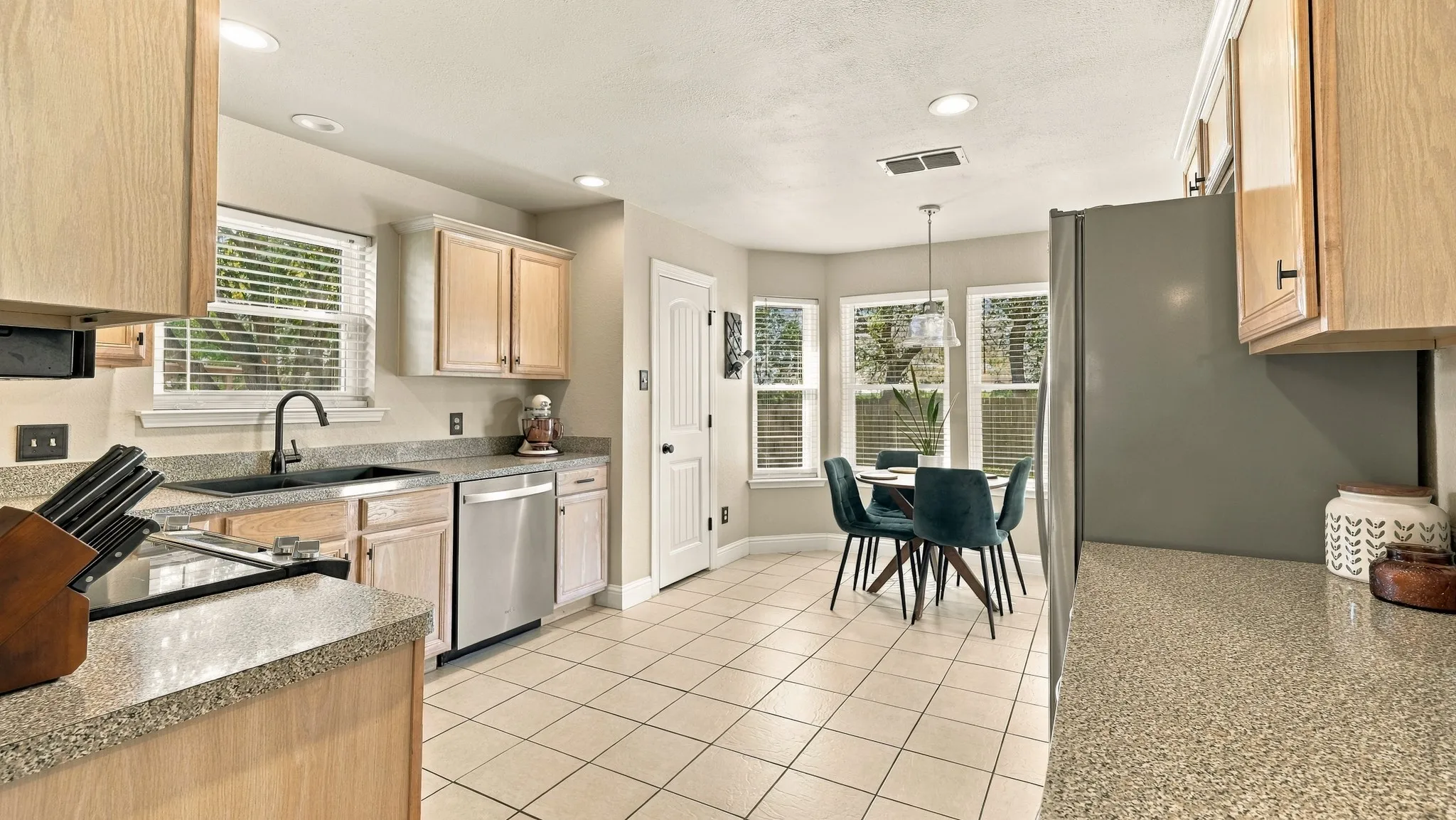 Kitchen featuring light wood cabinetry, stone-finish countertops, stainless steel appliances, and tile flooring