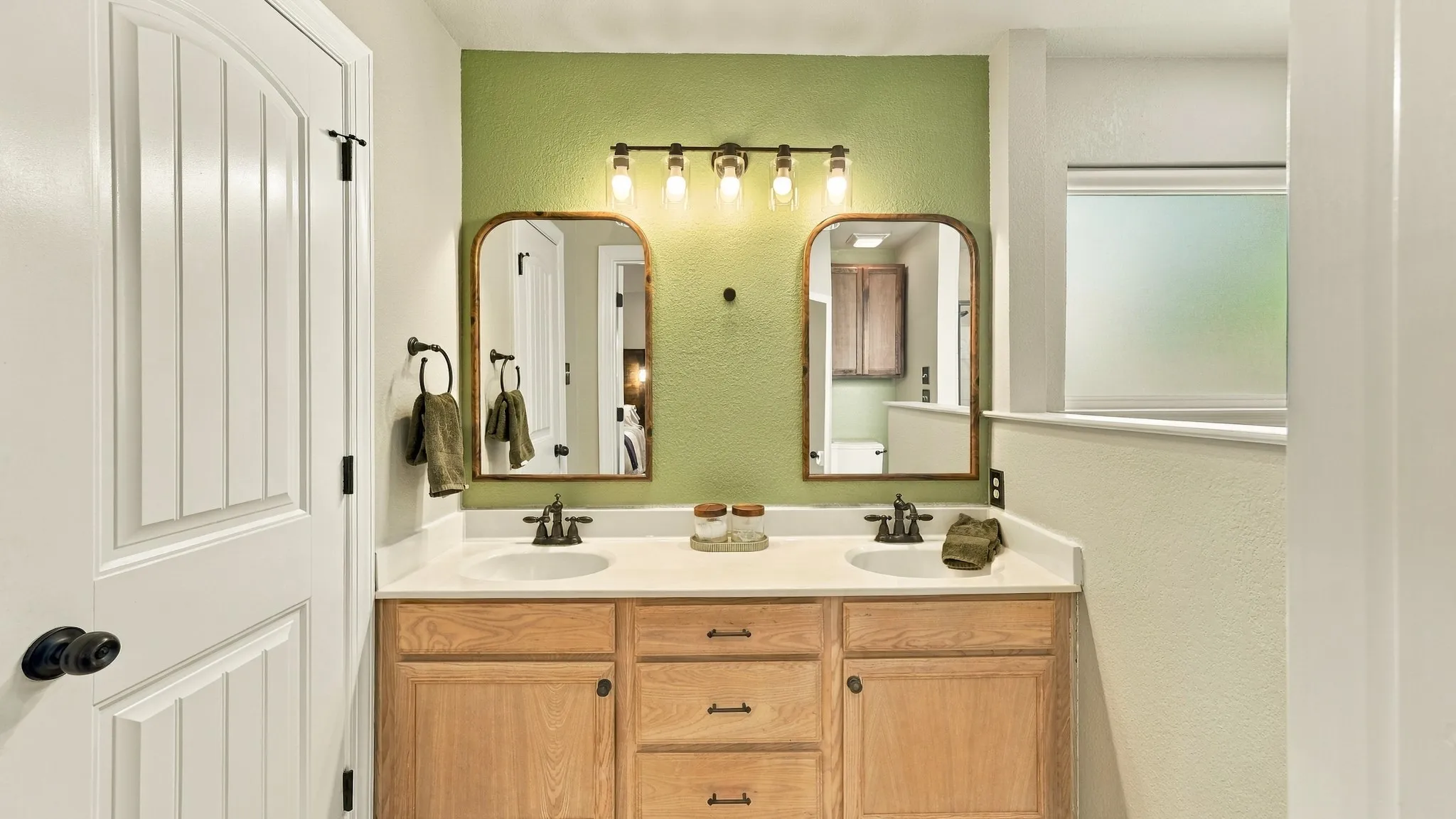Dual vanity with undermount sinks, wood-finish cabinetry, and a light-toned countertop