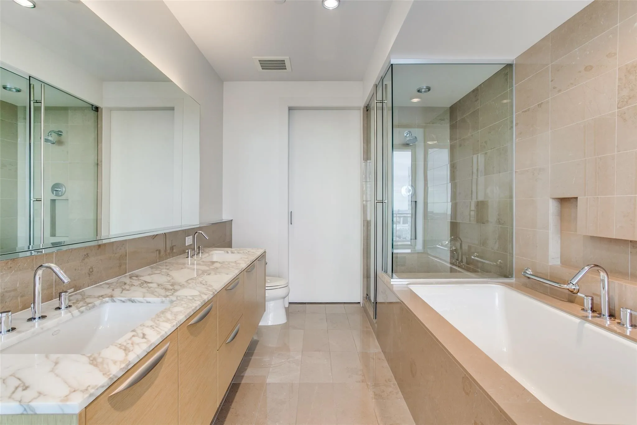 Dual vanity with a white stone countertop, built-in soaking tub, and glass-enclosed shower