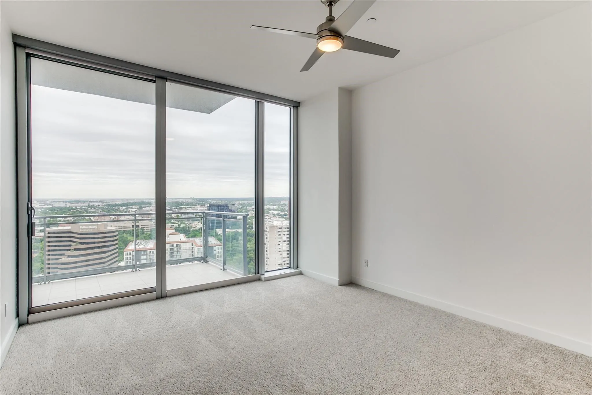 Expansive floor-to-ceiling windows, private balcony, and contemporary ceiling fan with integrated lighting