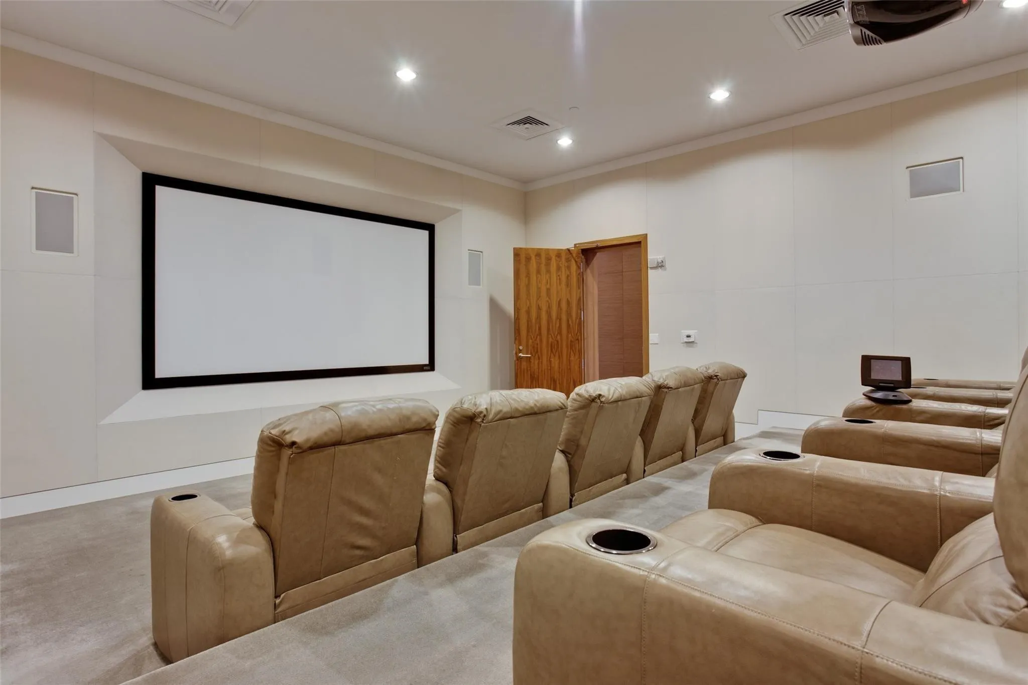 Dedicated media room with a large projection screen, recessed ceiling lighting, and built-in wall speakers