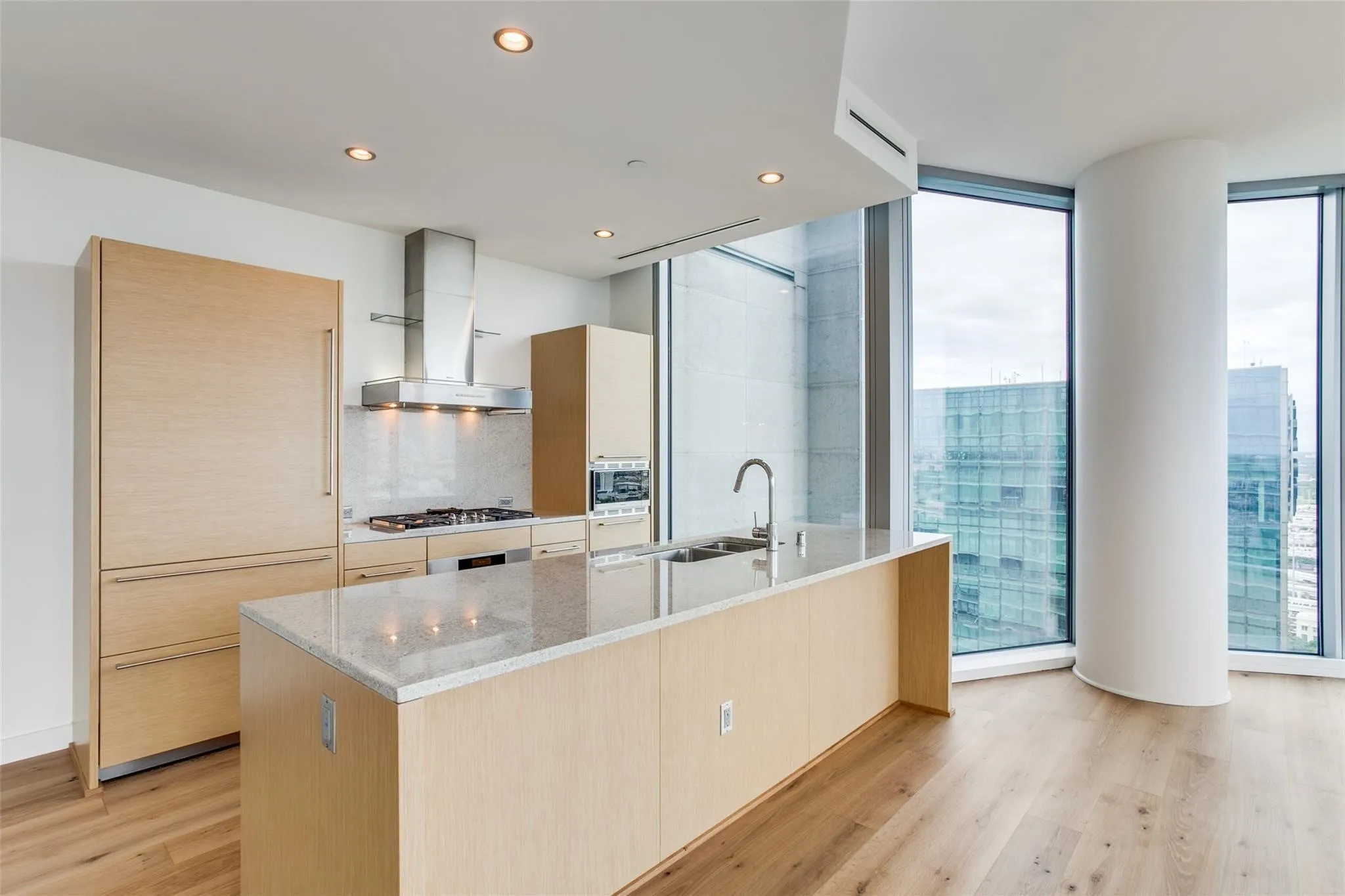 Gourmet kitchen featuring a large island with sink, stainless steel appliances, wood-finish cabinetry, and recessed lighting