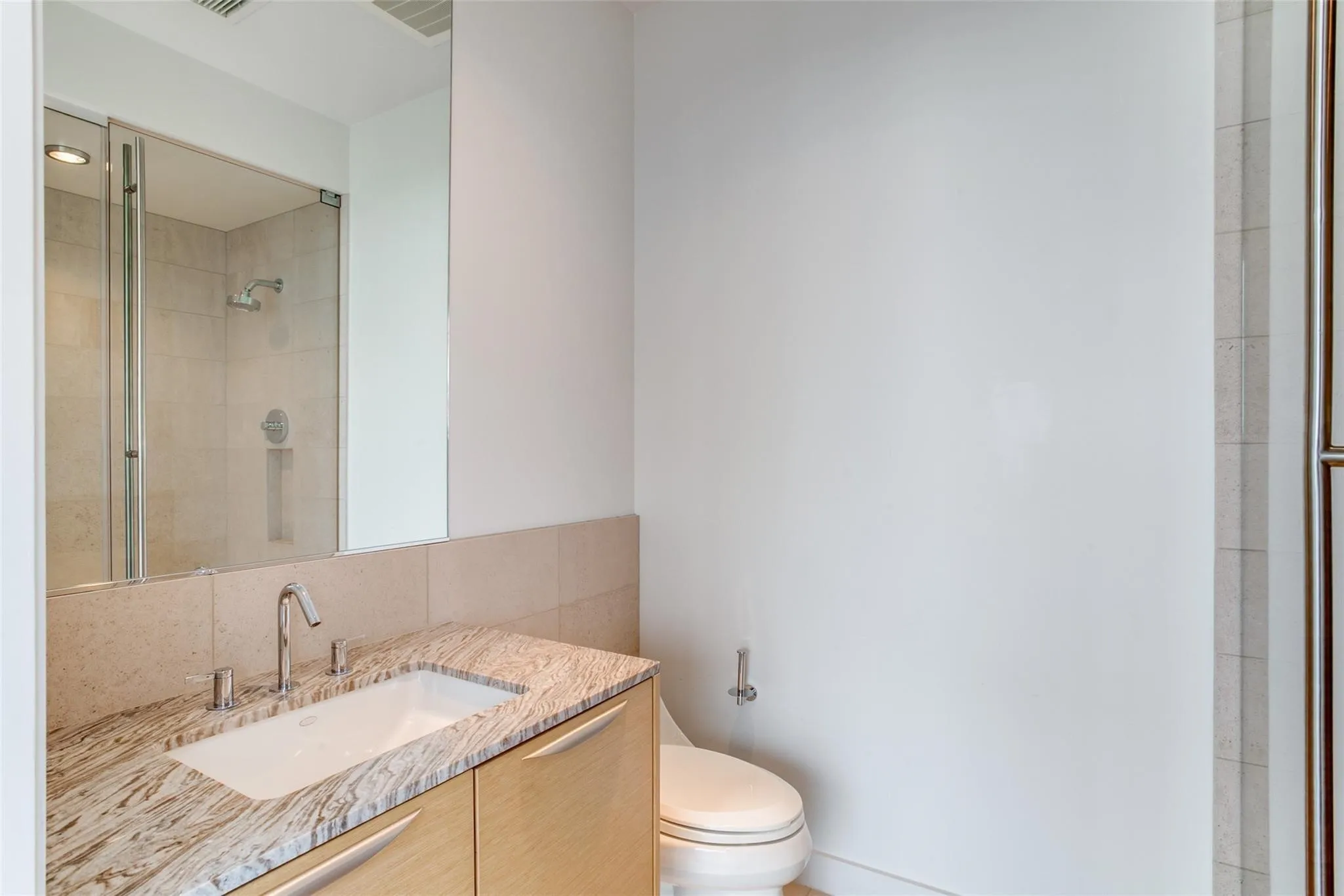 Vanity with a polished stone countertop, undermount sink, and wood-finish cabinetry