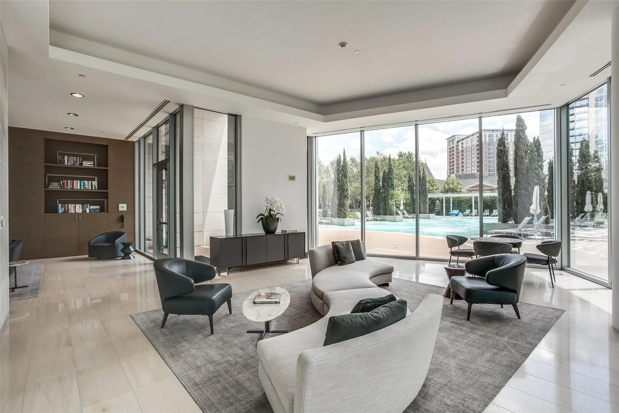 Extensive floor-to-ceiling windows, recessed lighting, built-in shelving, wood-finish wall panels, and a polished tile floor