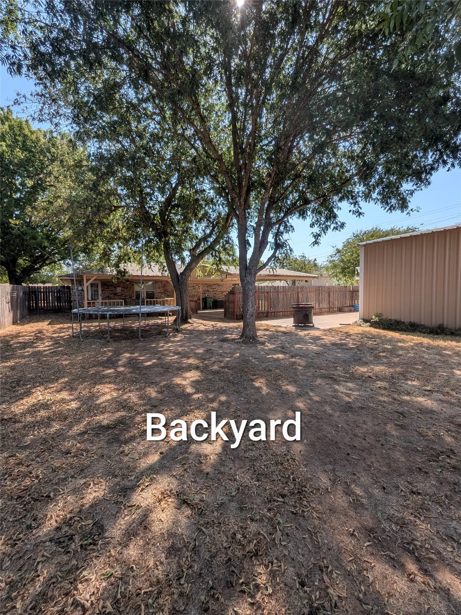Large backyard with big shade trees taken from back corner of yard