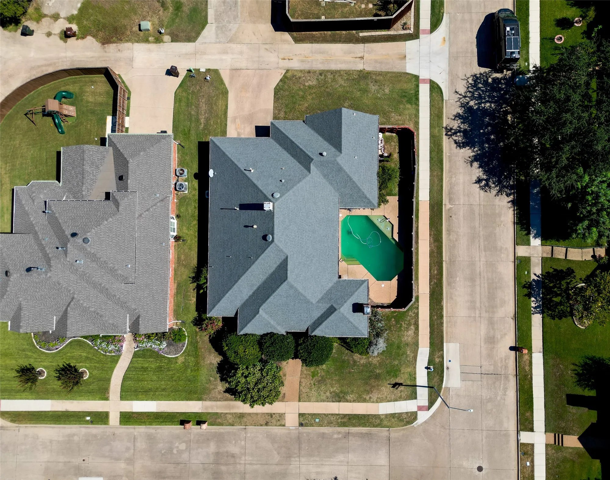Expansive property featuring a grey shingle roof, a backyard swimming pool, and a surrounding privacy fence