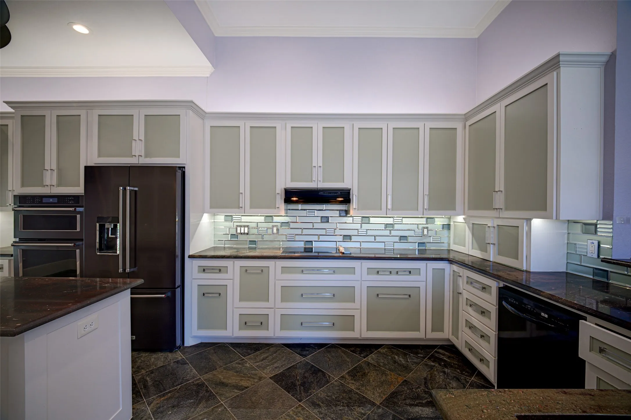 Kitchen with frosted glass-front upper cabinetry, dark stone countertops, mosaic tile backsplash, and built-in stainless steel appliances