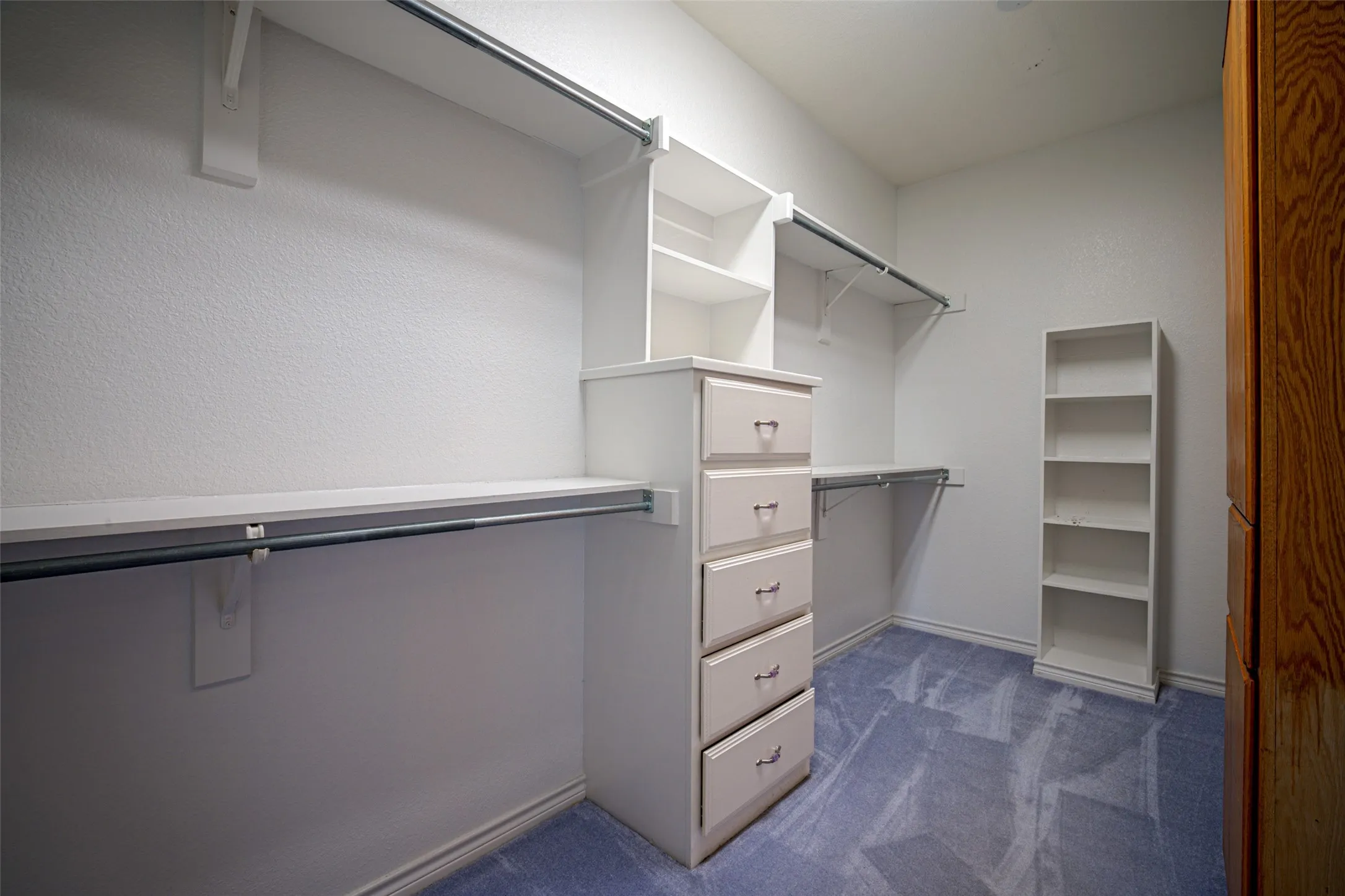 Built-in closet system featuring shelving, hanging rods, and a five-drawer dresser
