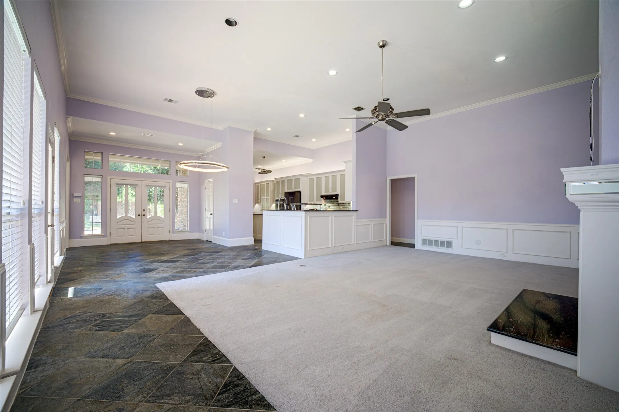 Vaulted ceiling, recessed lighting, ceiling fan, fireplace with stone hearth, and white wainscoting