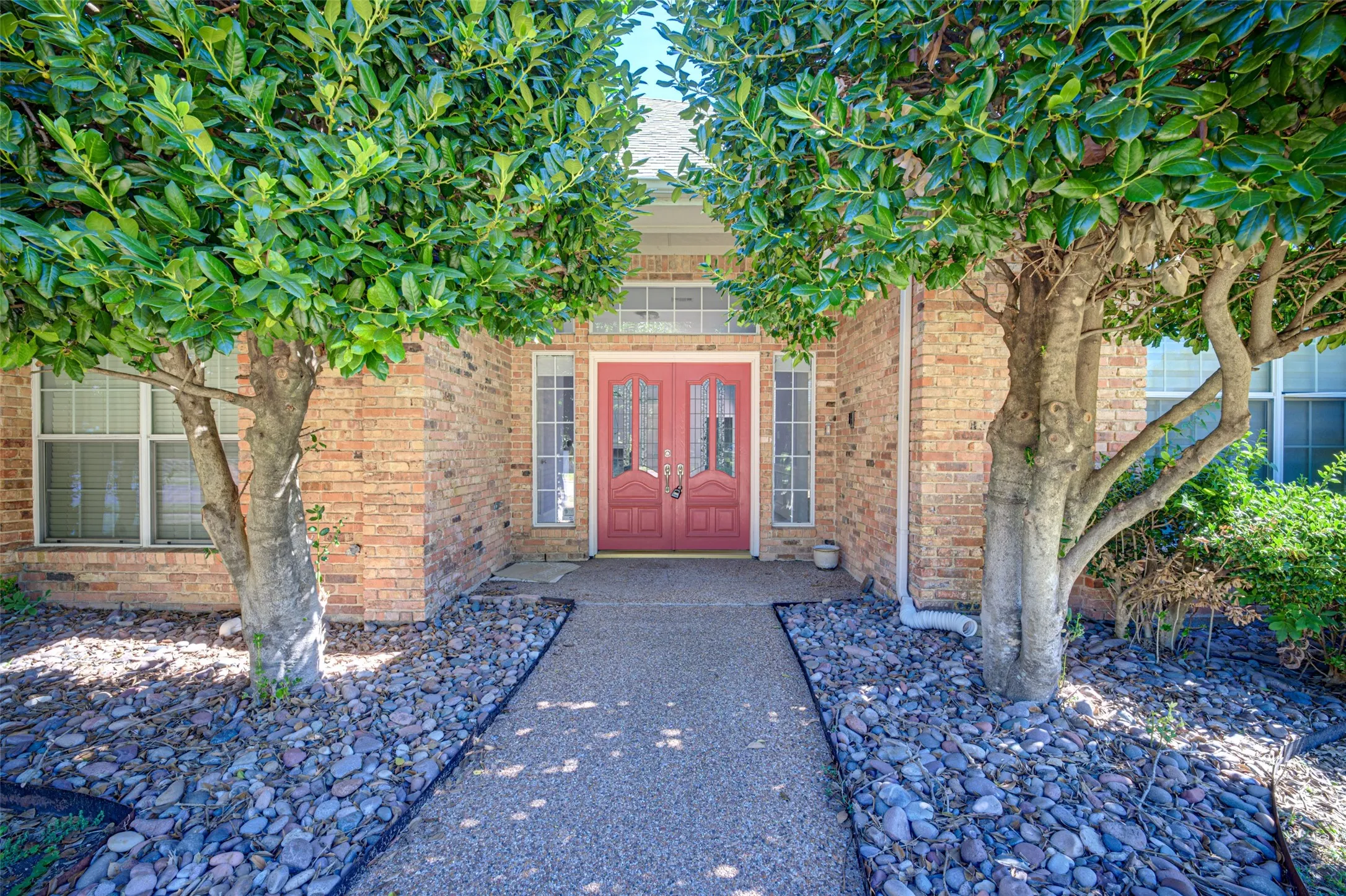 Brick exterior featuring a recessed entry, red double doors with decorative glass, and a transom window