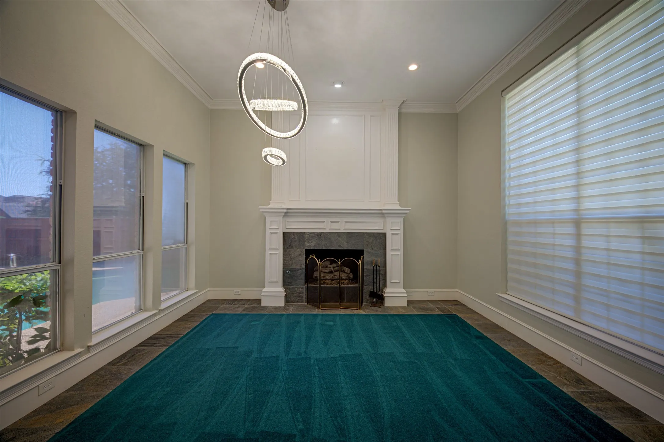 White mantel fireplace with stone surround, complemented by a modern multi-ring chandelier