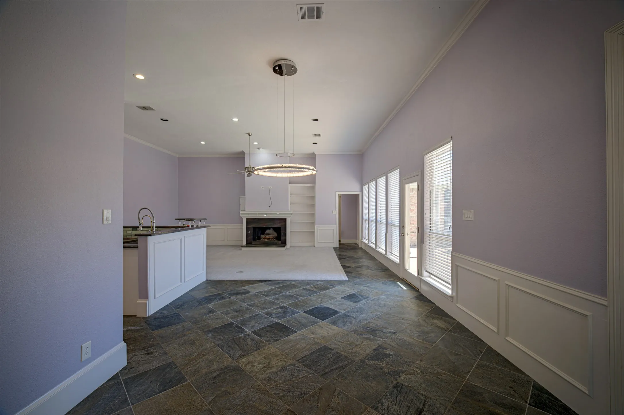 Slate tile flooring, high ceilings, recessed lighting, built-in fireplace, and wainscoting