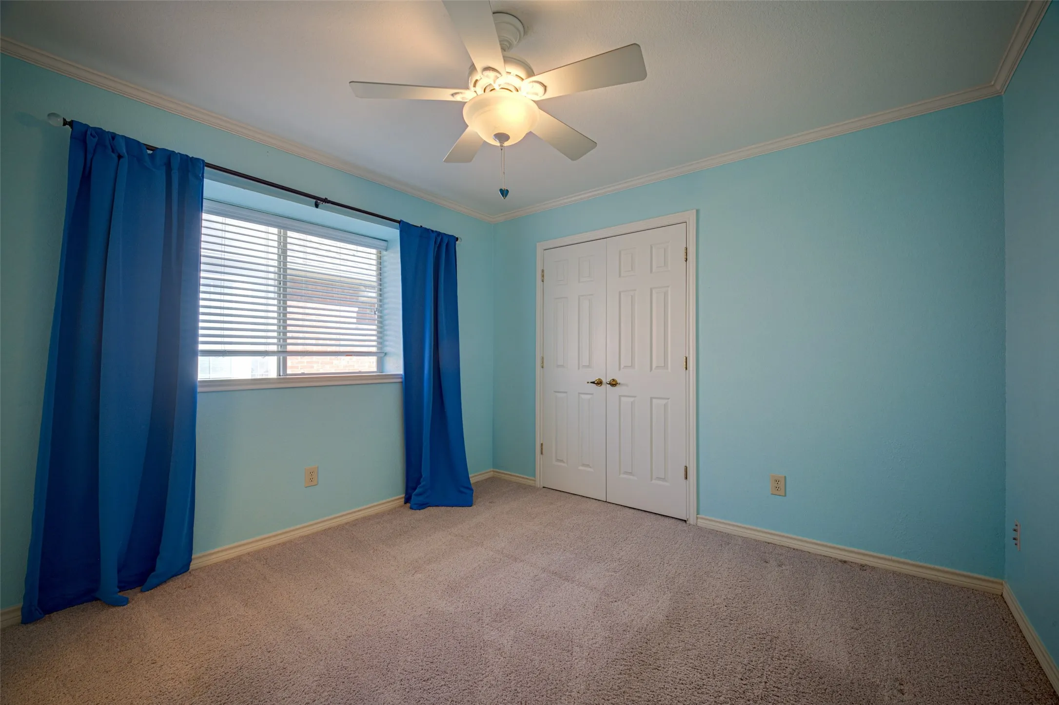 Ceiling fan fixture, window with horizontal blinds, bi-fold closet doors, wall-to-wall carpeting, and crown molding