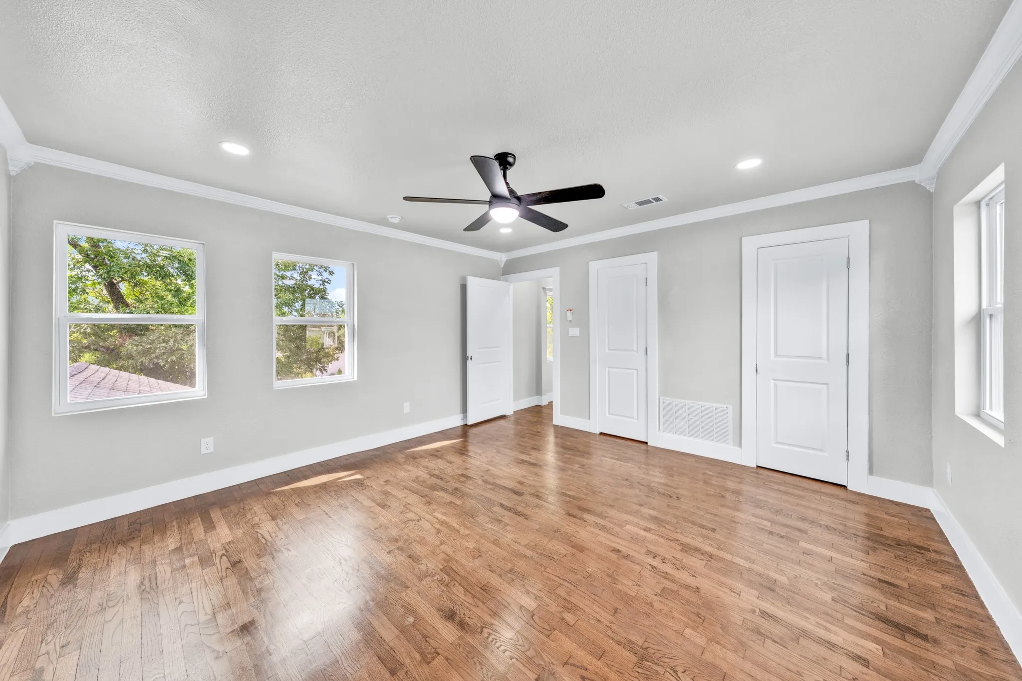 Hardwood flooring, recessed lighting, crown molding, multiple windows, and a ceiling fan