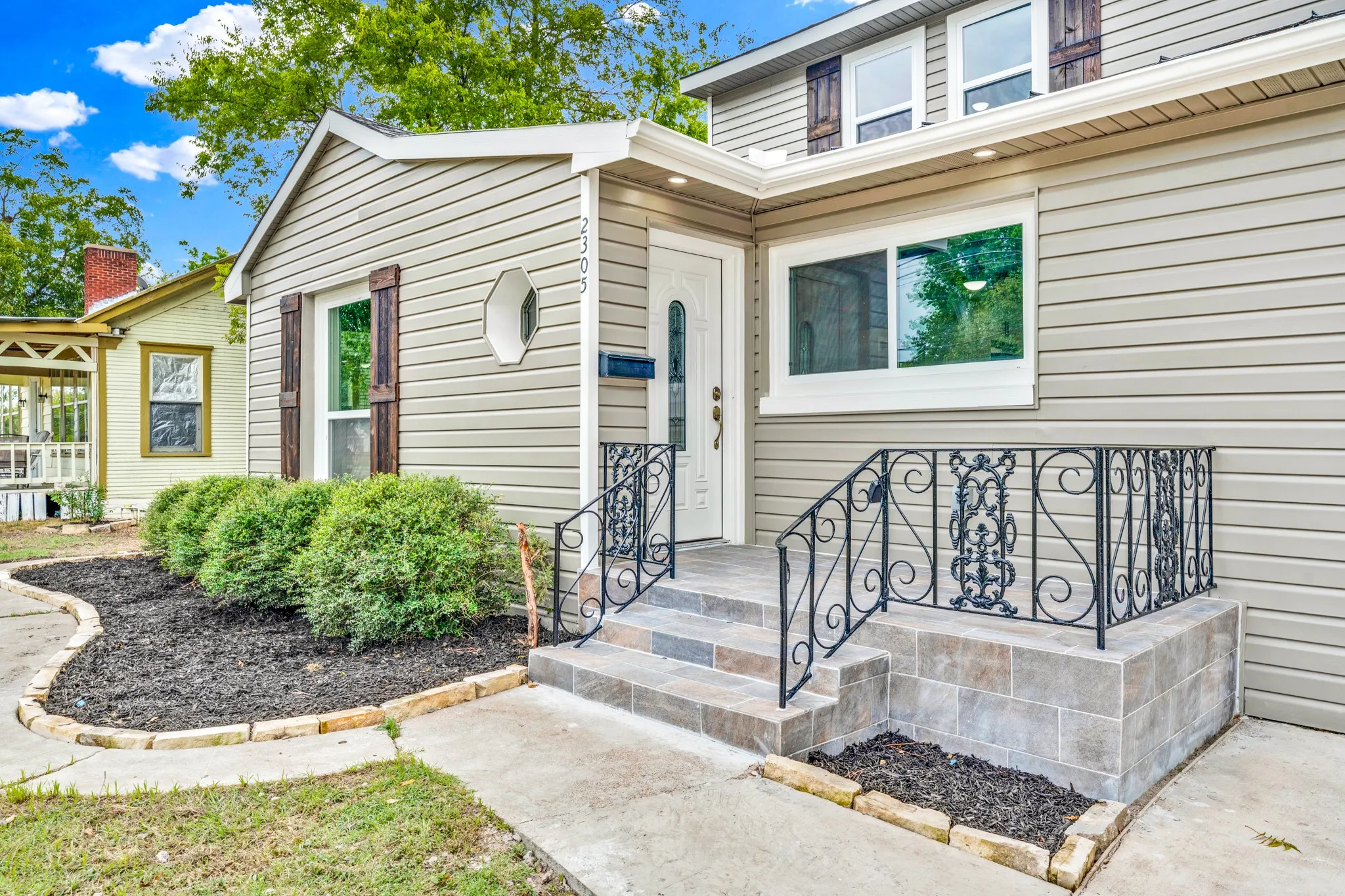 Siding exterior with decorative window shutters and a tiled entry porch