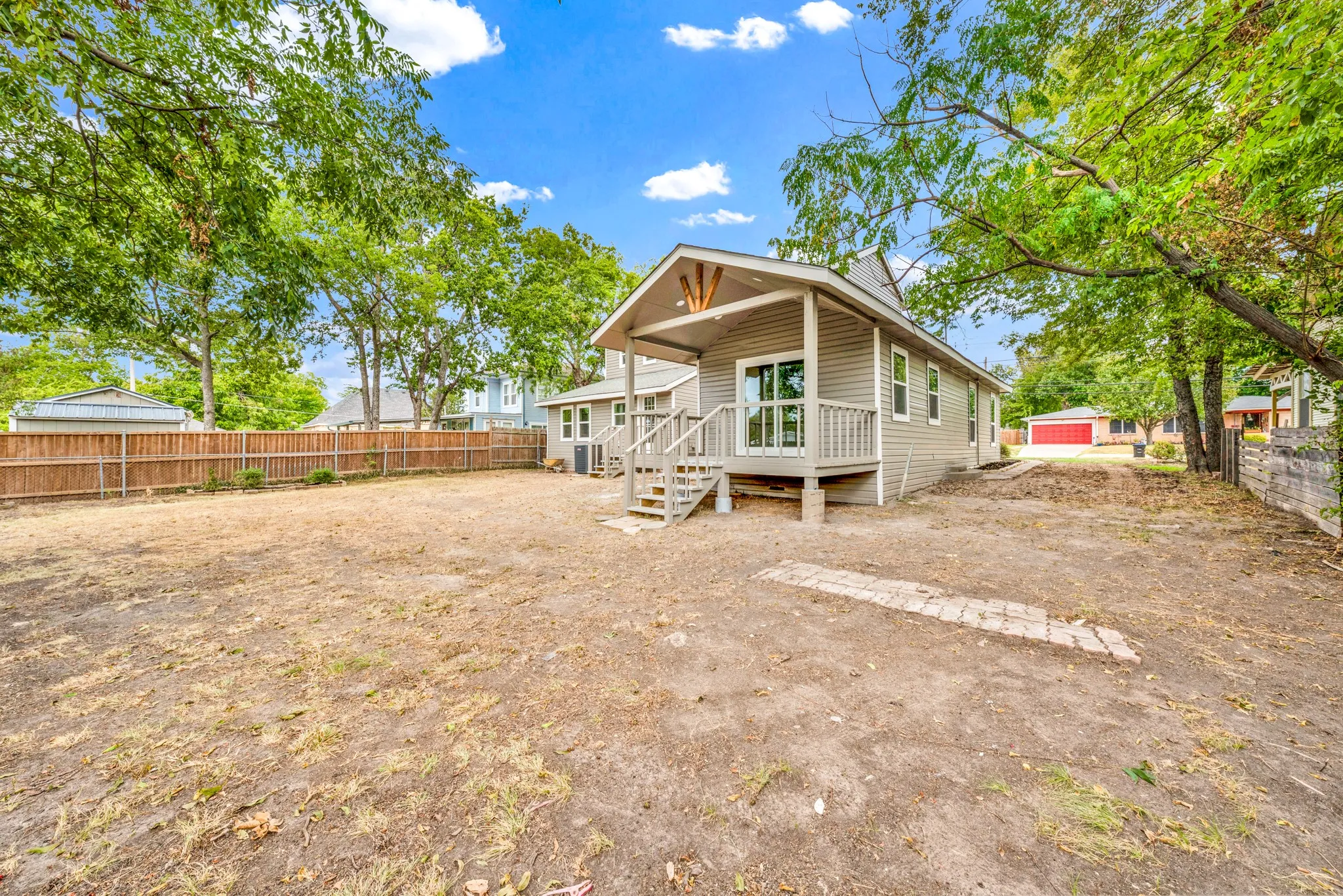 Expansive property featuring a wood privacy fence, mature trees, and a raised exterior deck with steps