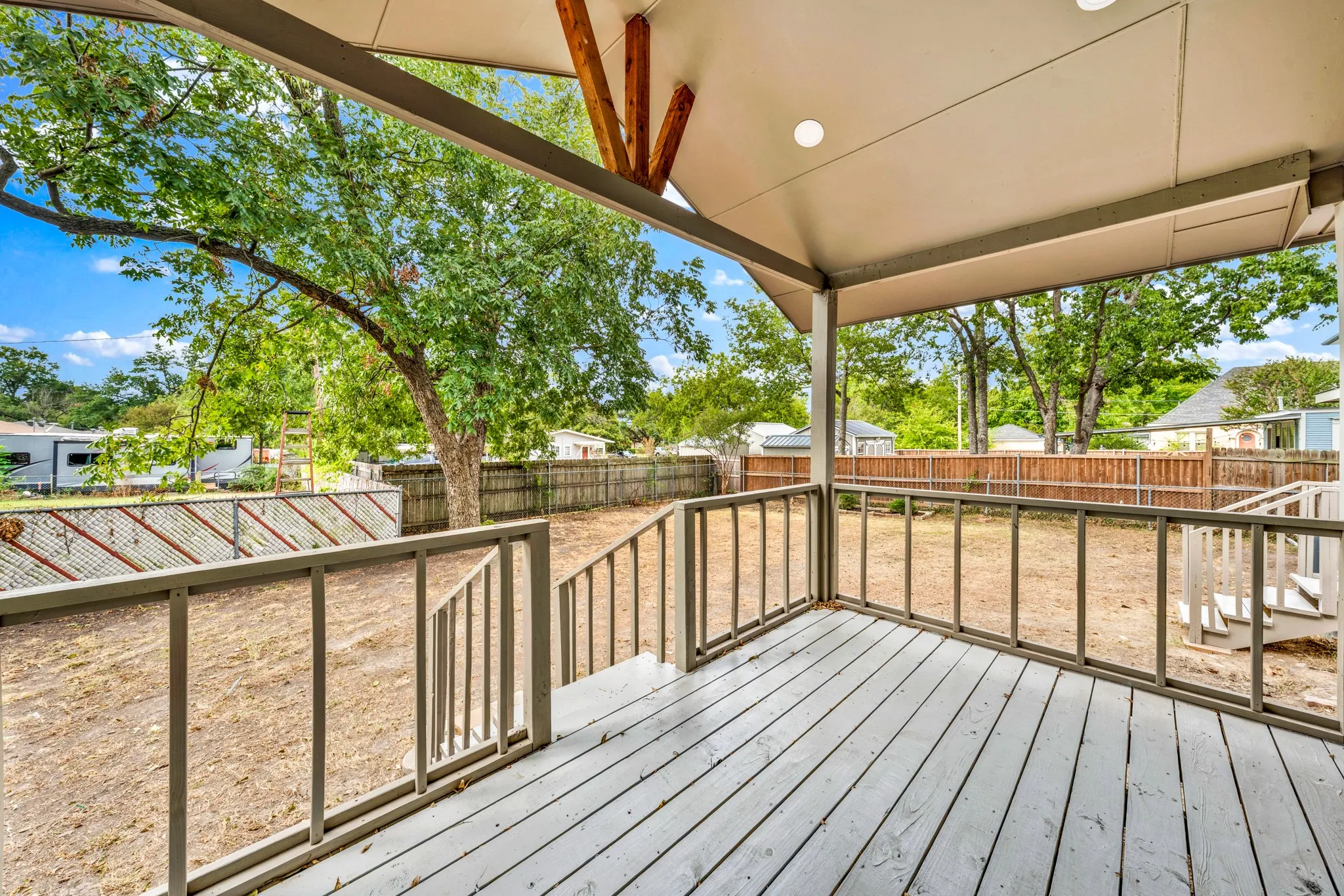 Covered outdoor deck with light-toned wood-finish flooring, recessed lighting, and a sloped ceiling