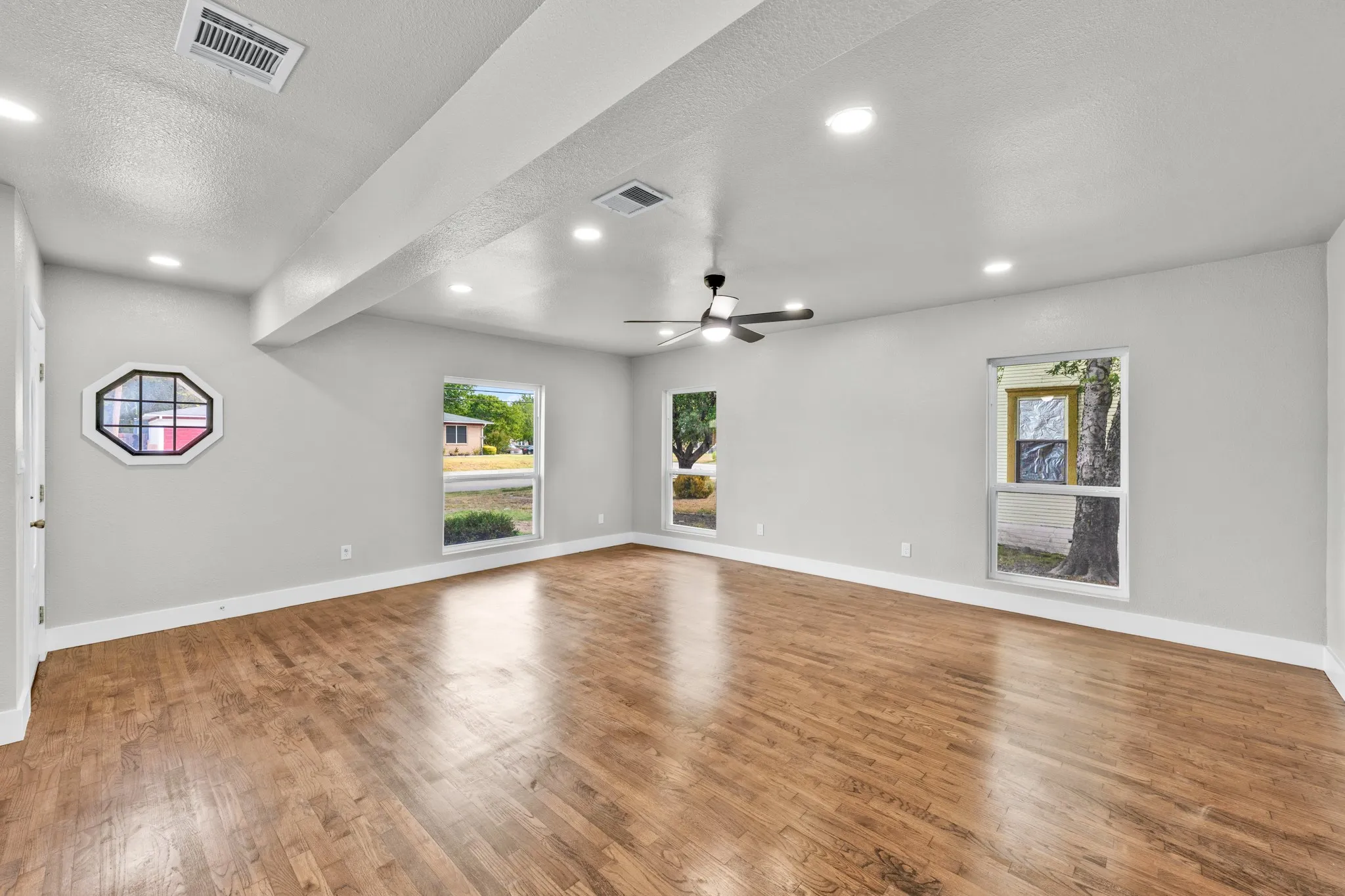 Spacious room featuring wood-finish flooring, recessed lighting, and a ceiling fan