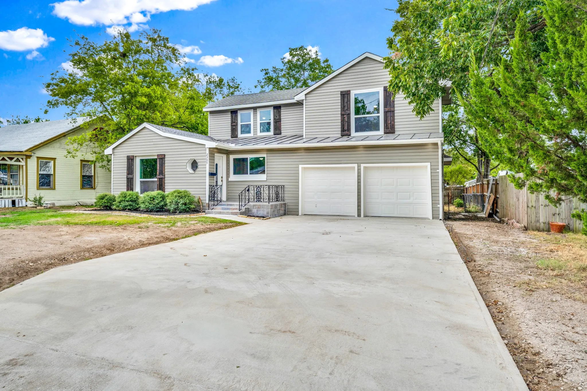 Two-story siding exterior with contrasting window shutters, two-car garage, and a concrete driveway