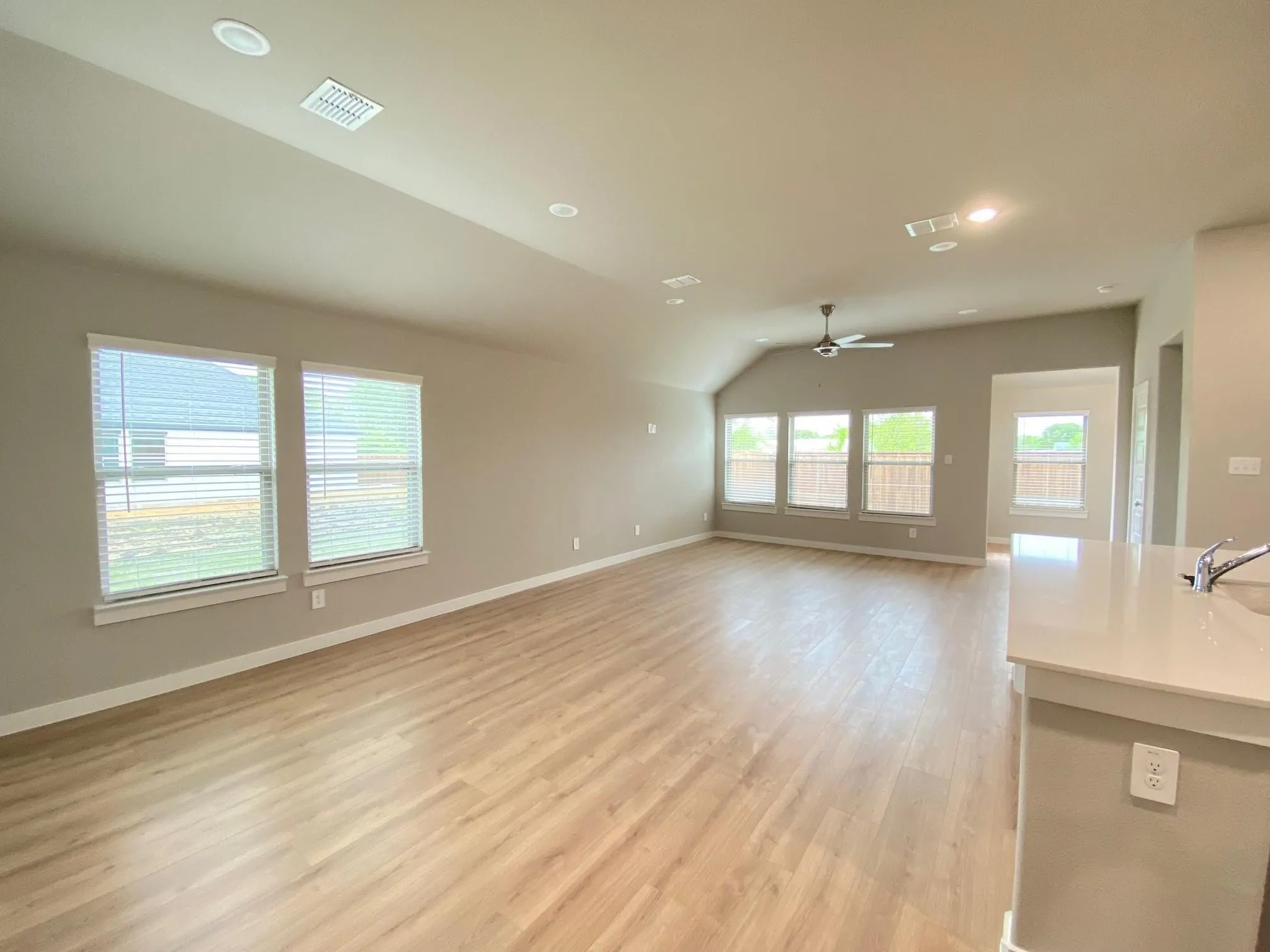 Spacious room with wood-finish flooring, recessed lighting, and multiple windows with blinds