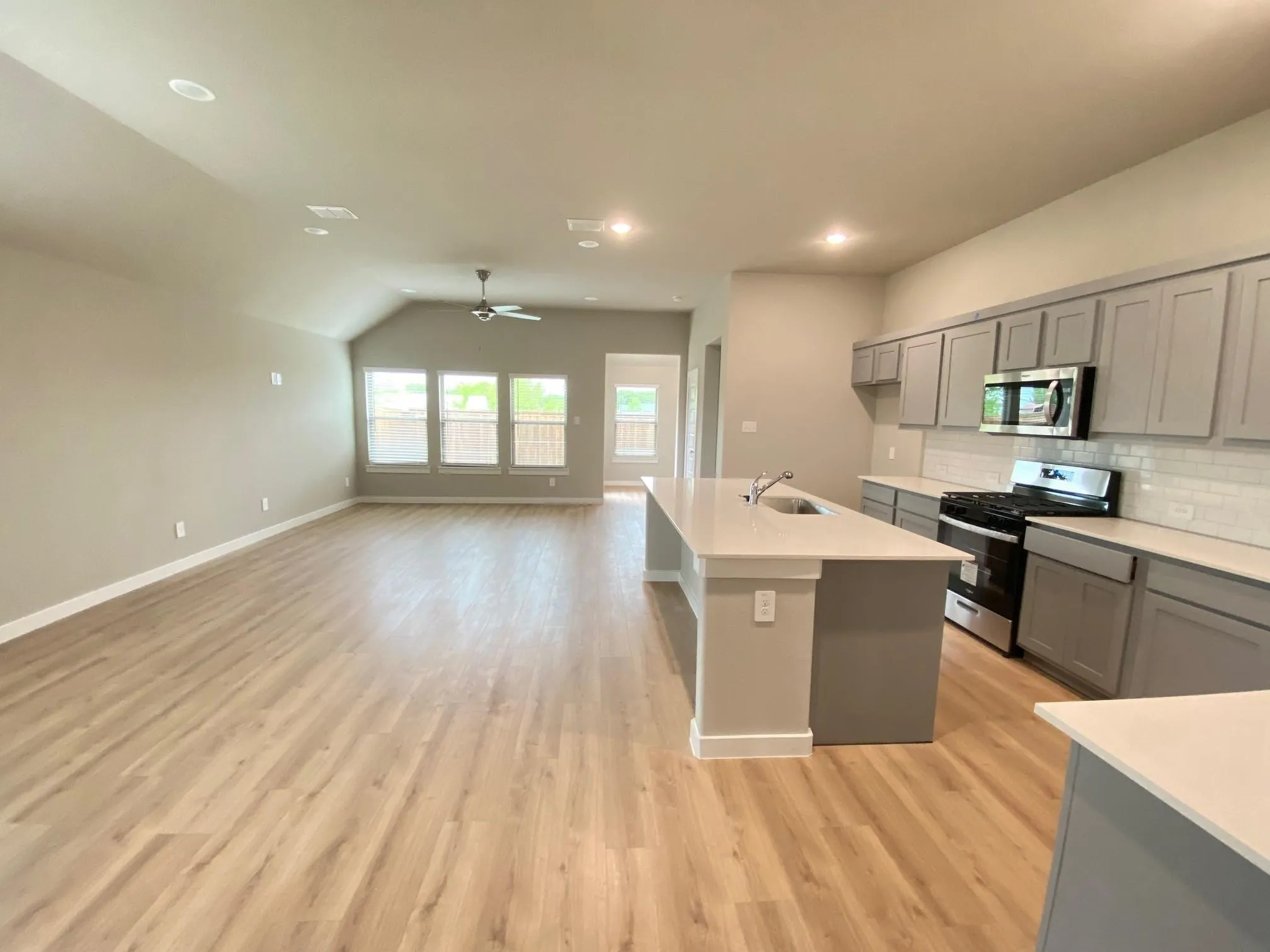 Open-concept living space featuring wood-finish flooring, recessed lighting, and a vaulted ceiling
