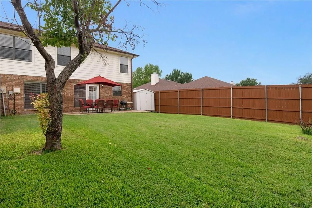 Expansive backyard with a large lawn, privacy fencing, and an exterior storage shed