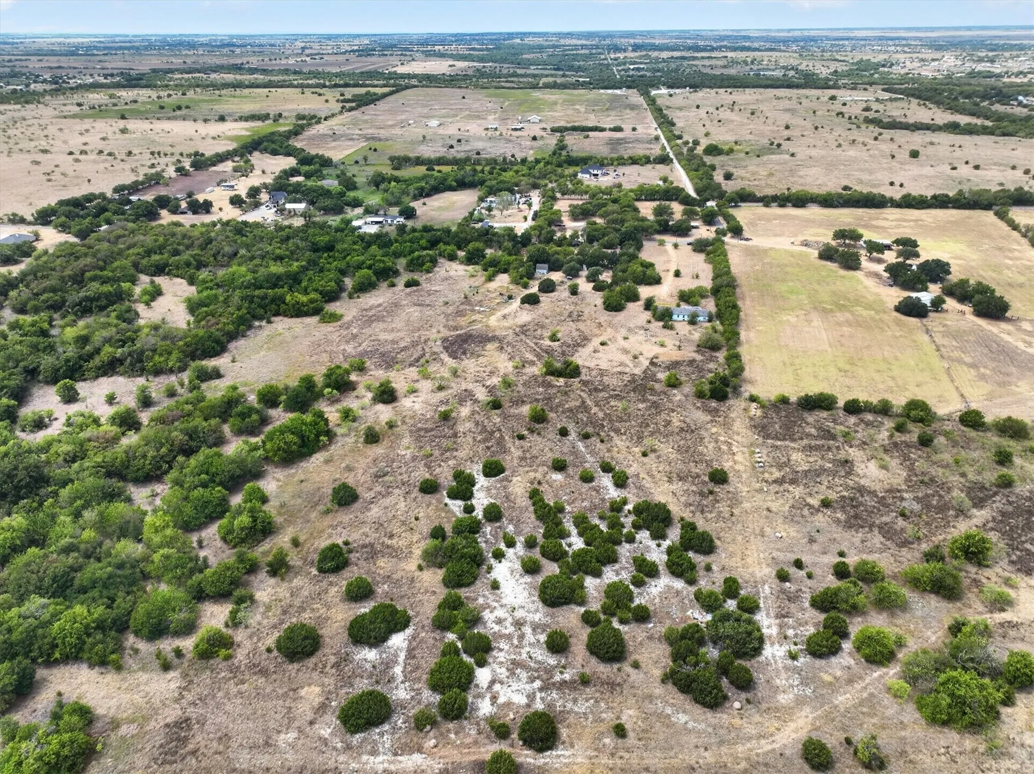 Expansive rural landscape featuring a mix of cleared land and clustered trees