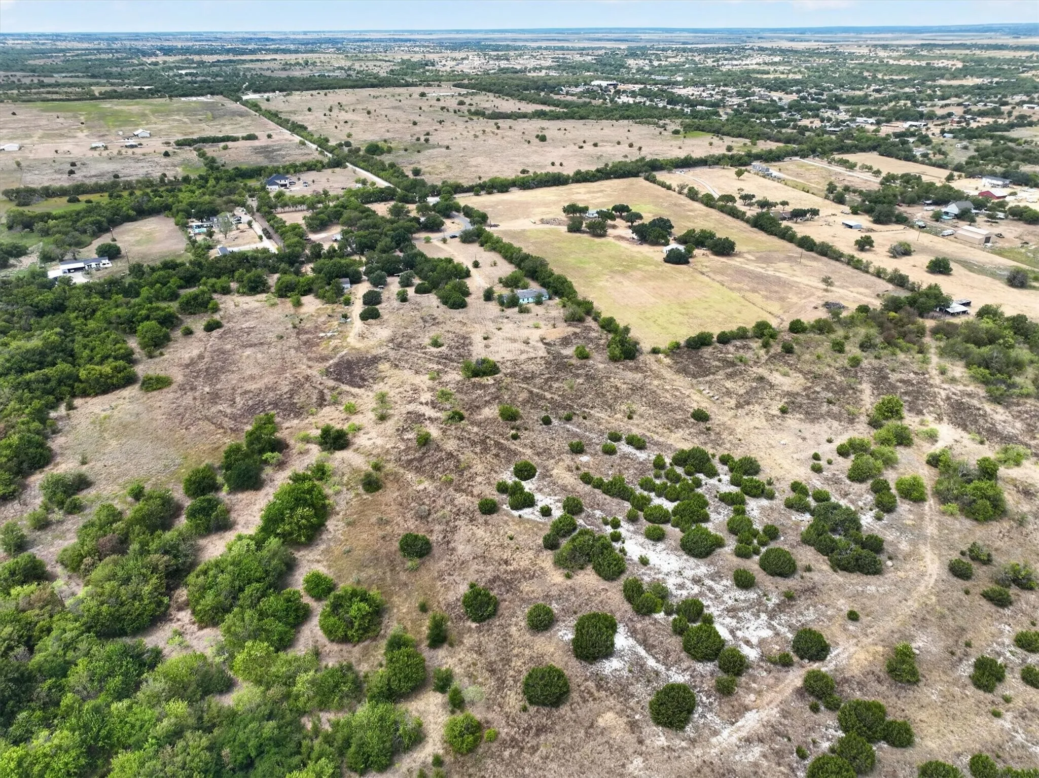 Expansive land parcel featuring varied terrain, scattered trees, and distant developed areas