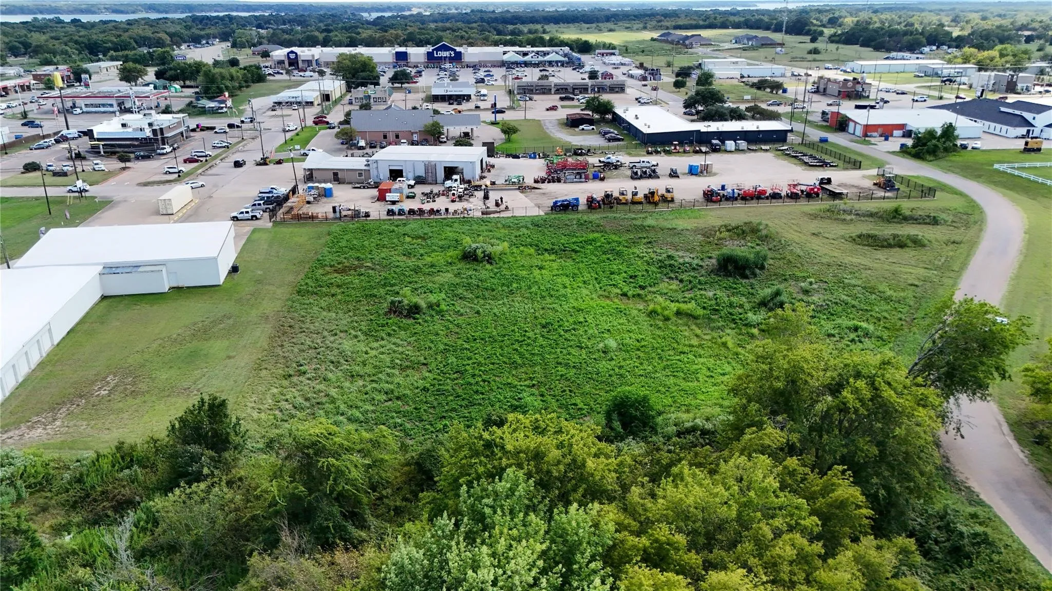 Expansive green space bordered by mature trees and paved roadways