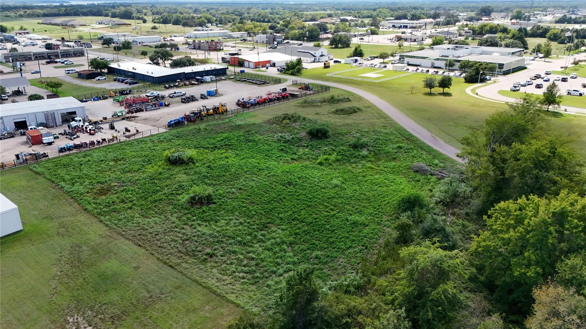 Expansive undeveloped land featuring natural vegetation and surrounding commercial structures