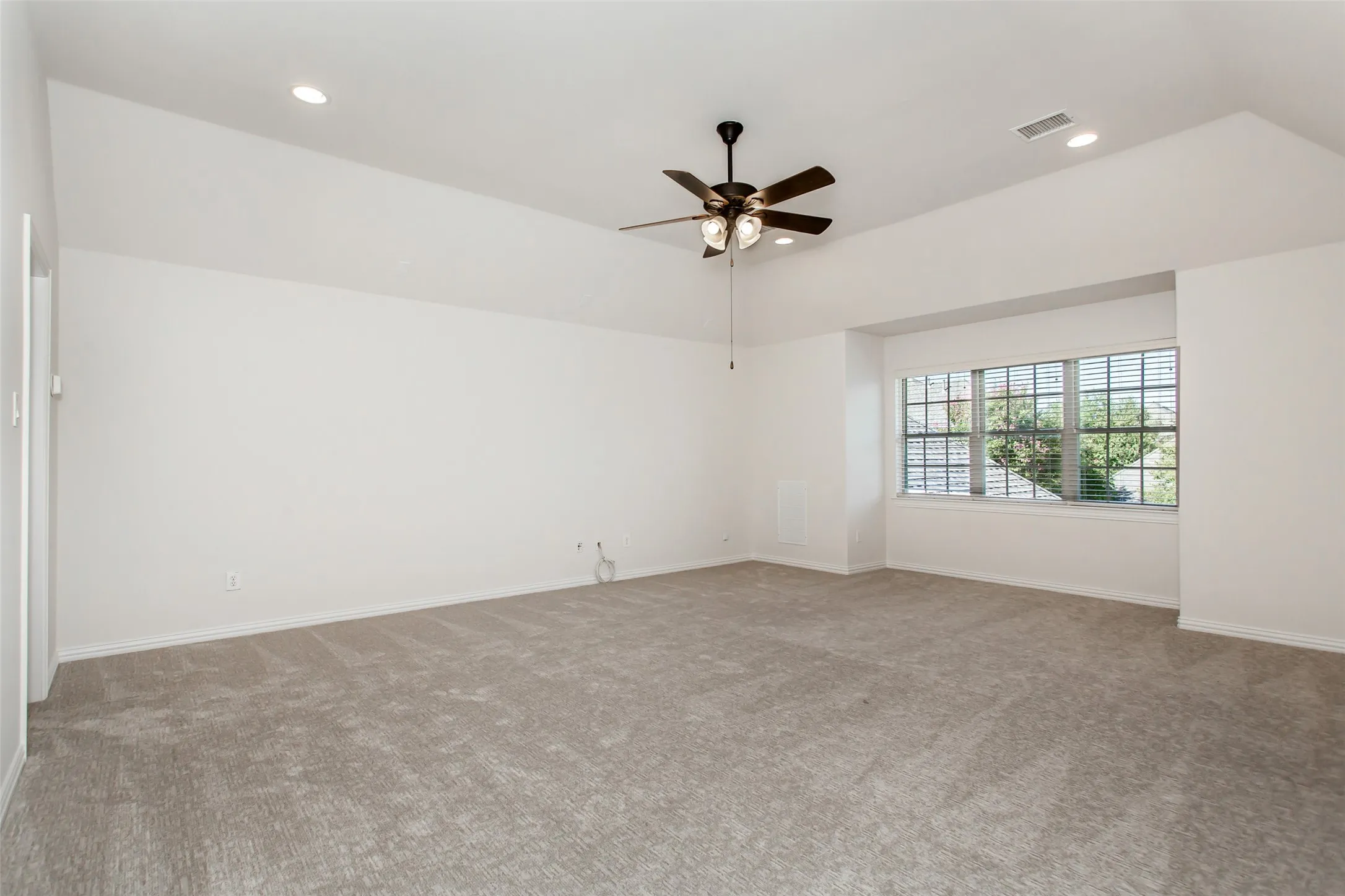 Vaulted ceiling with recessed lighting and a ceiling fan, carpeted flooring, and a multi-pane window with blinds