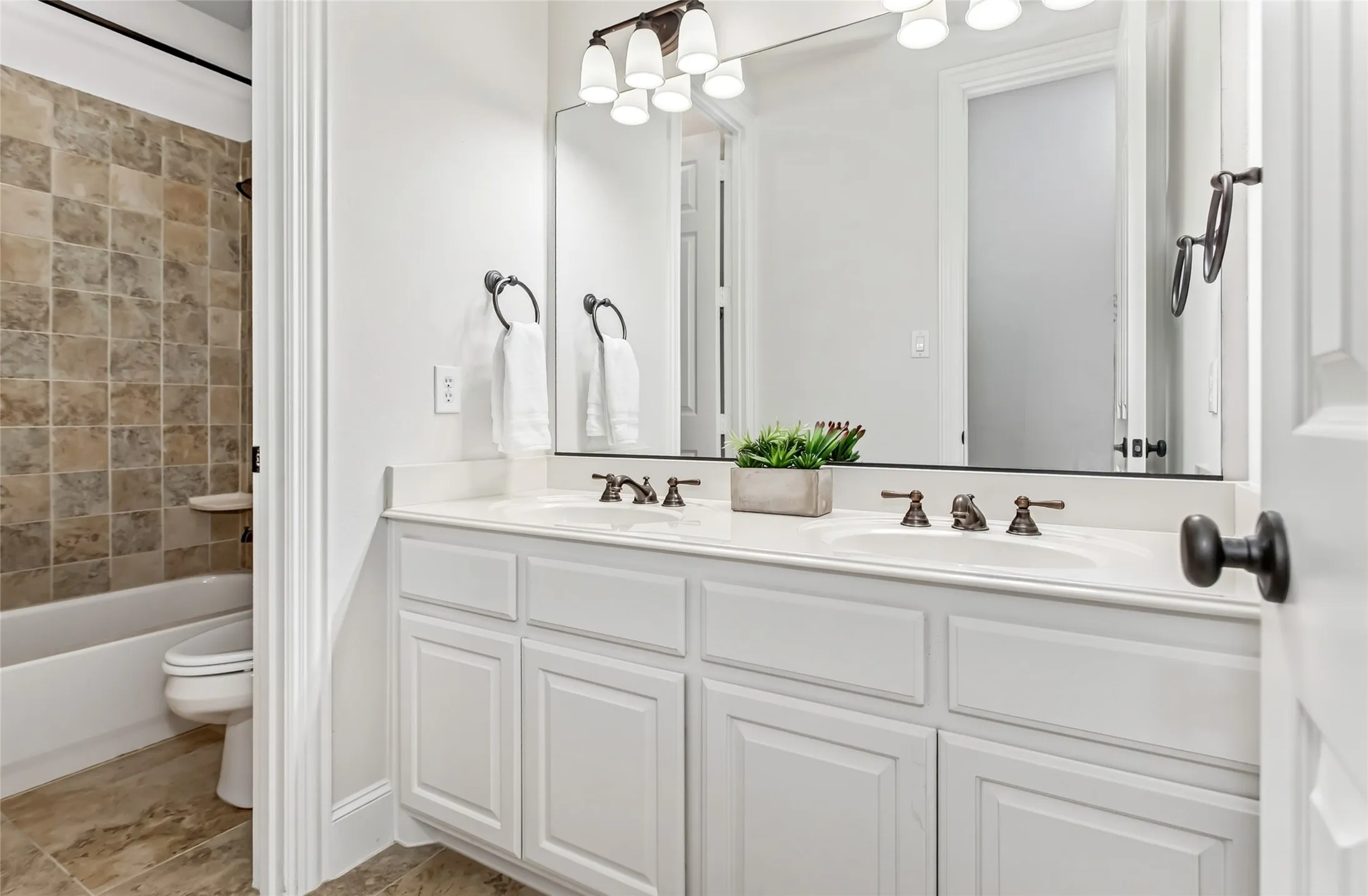 Dual sink vanity with white cabinetry, polished nickel hardware, and a large framed mirror