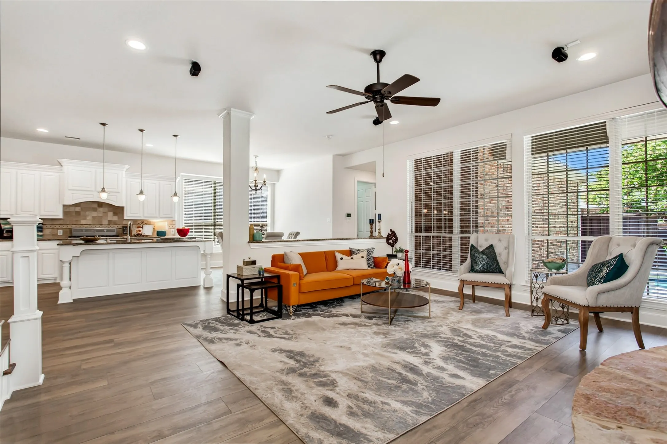 Wood-finish flooring, recessed lighting, ceiling fan, white cabinetry, and large windows