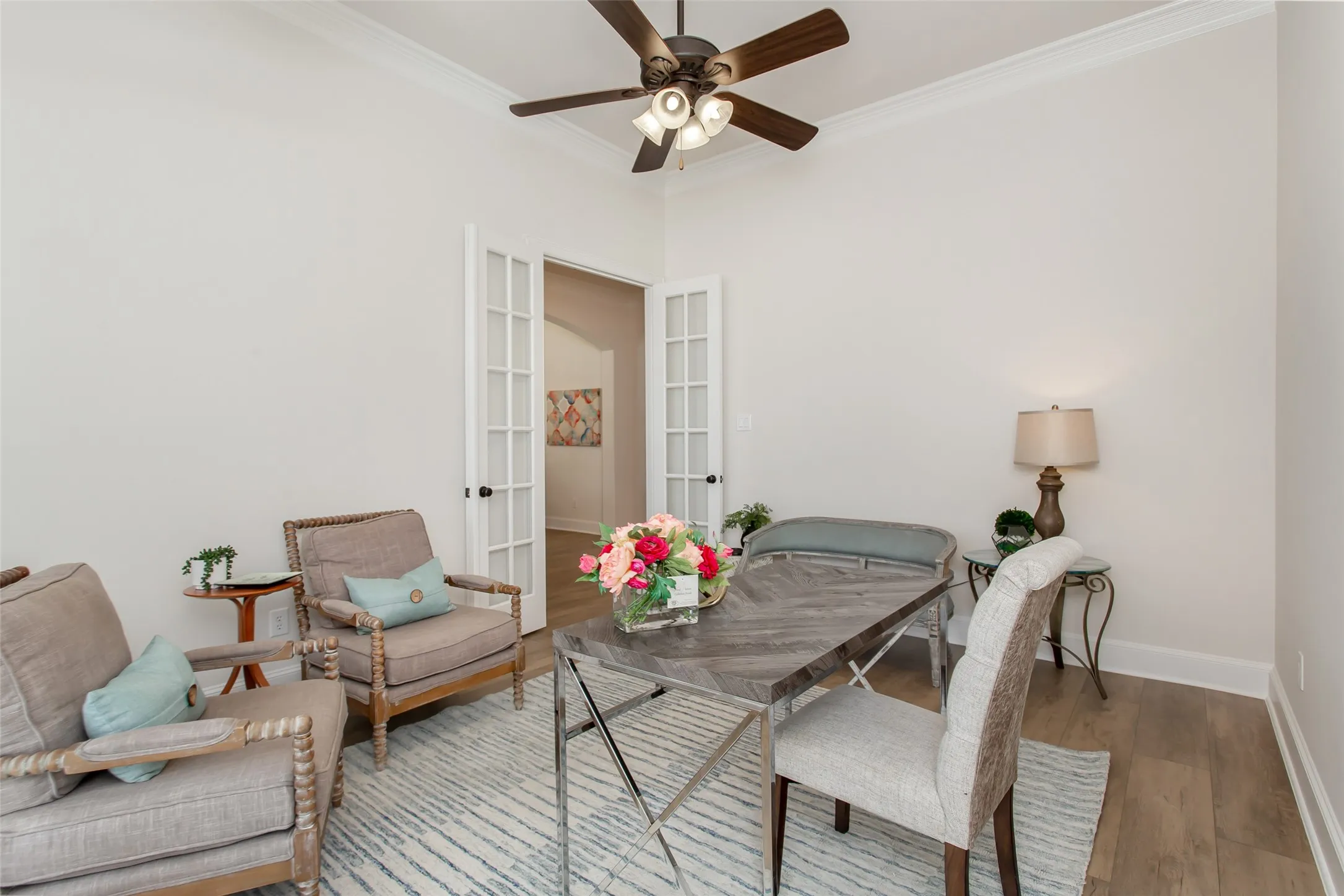 Wood-finish flooring, crown molding, and a ceiling fan with integrated lighting