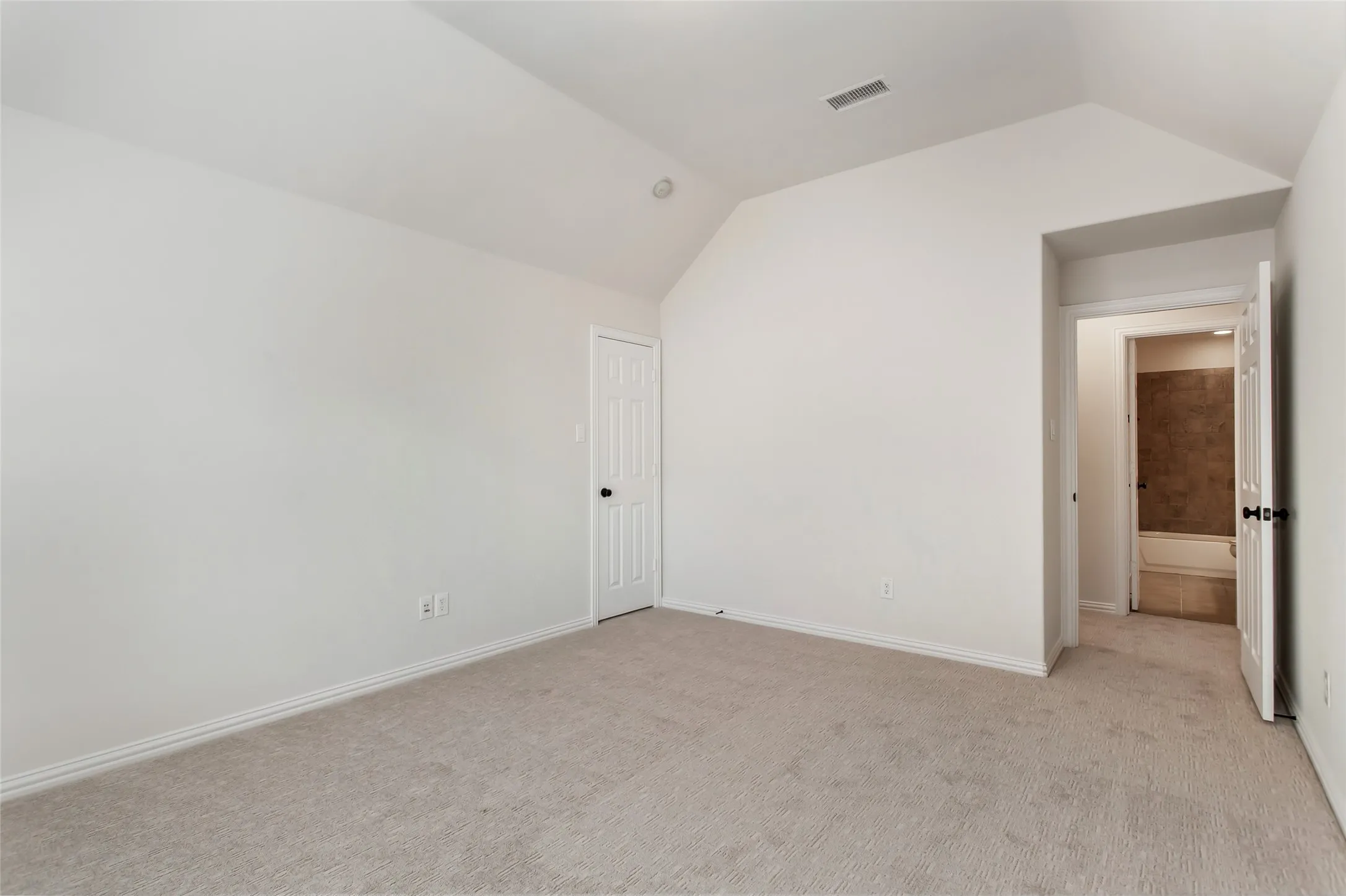 2nd floor bedroom. Vaulted ceiling, recessed lighting, neutral carpeting, white trim, and a paneled door