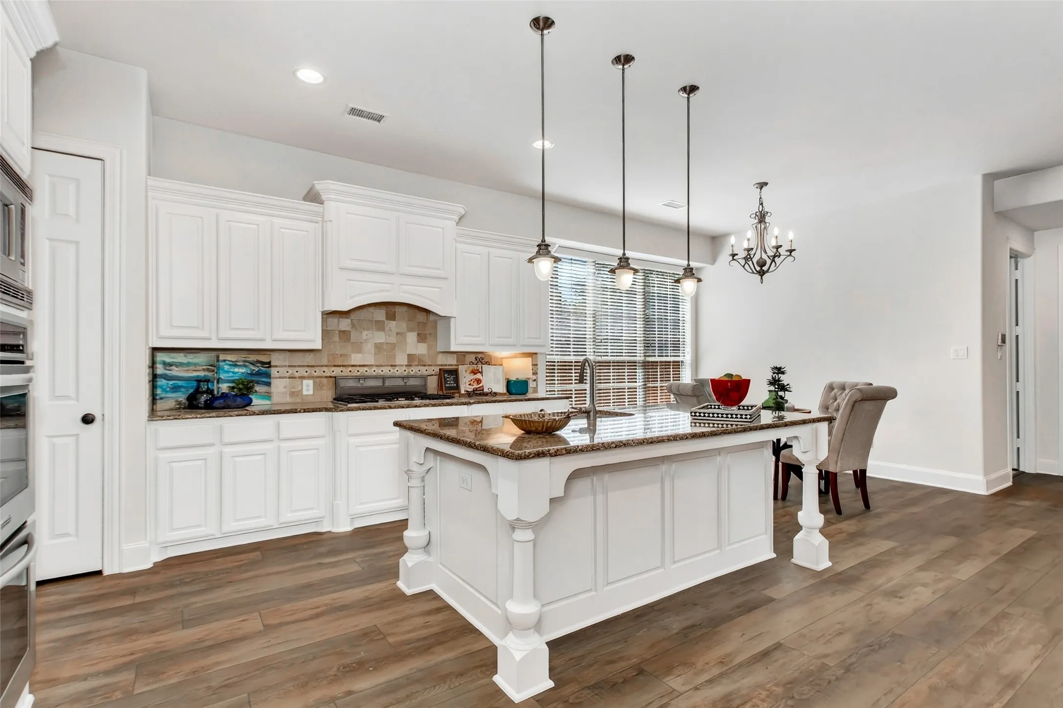 Kitchen featuring white cabinetry, stone countertops, a central island with seating, a tile backsplash, and wood-finish flooring