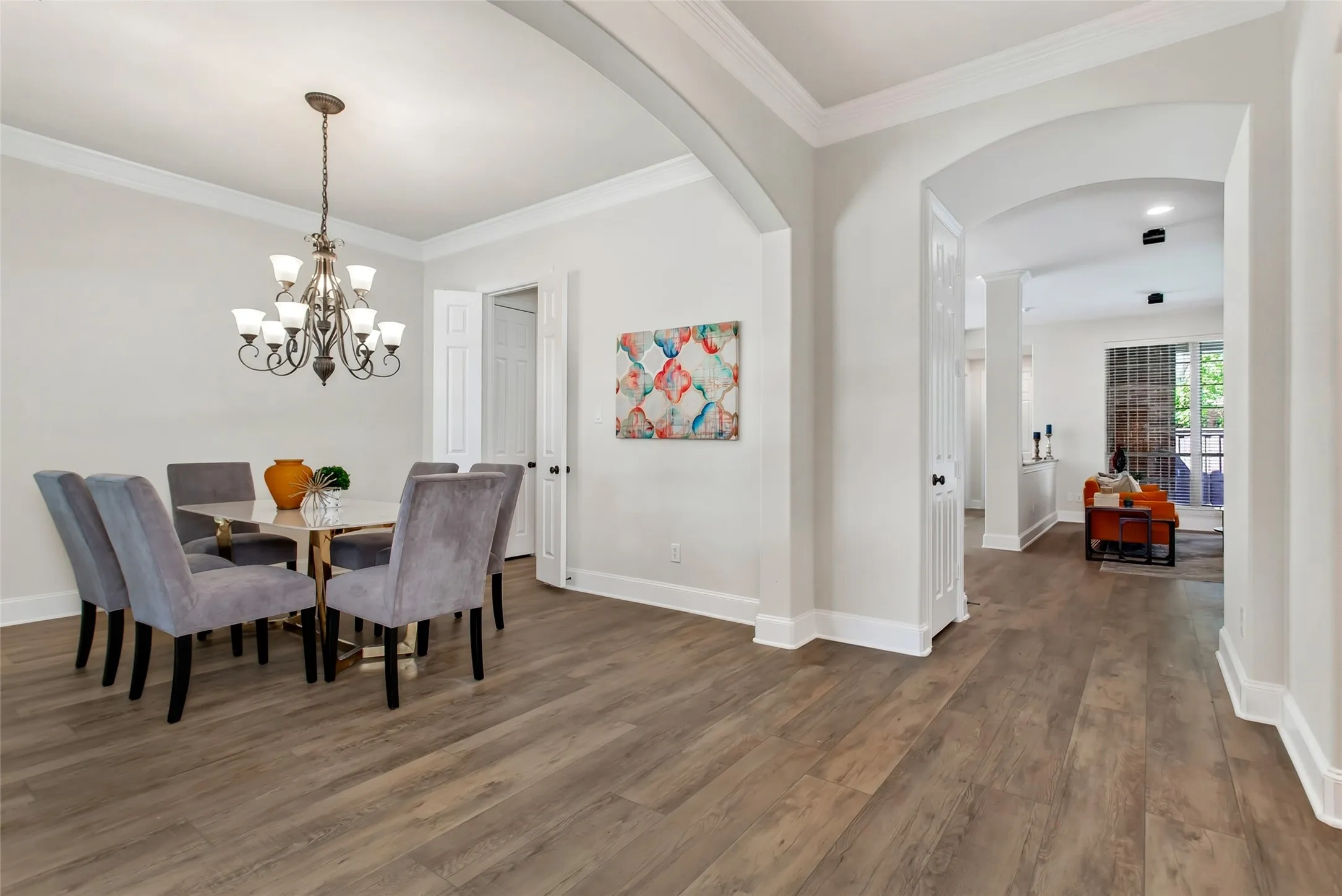 Wood-finish flooring throughout, featuring arched doorways and crown molding