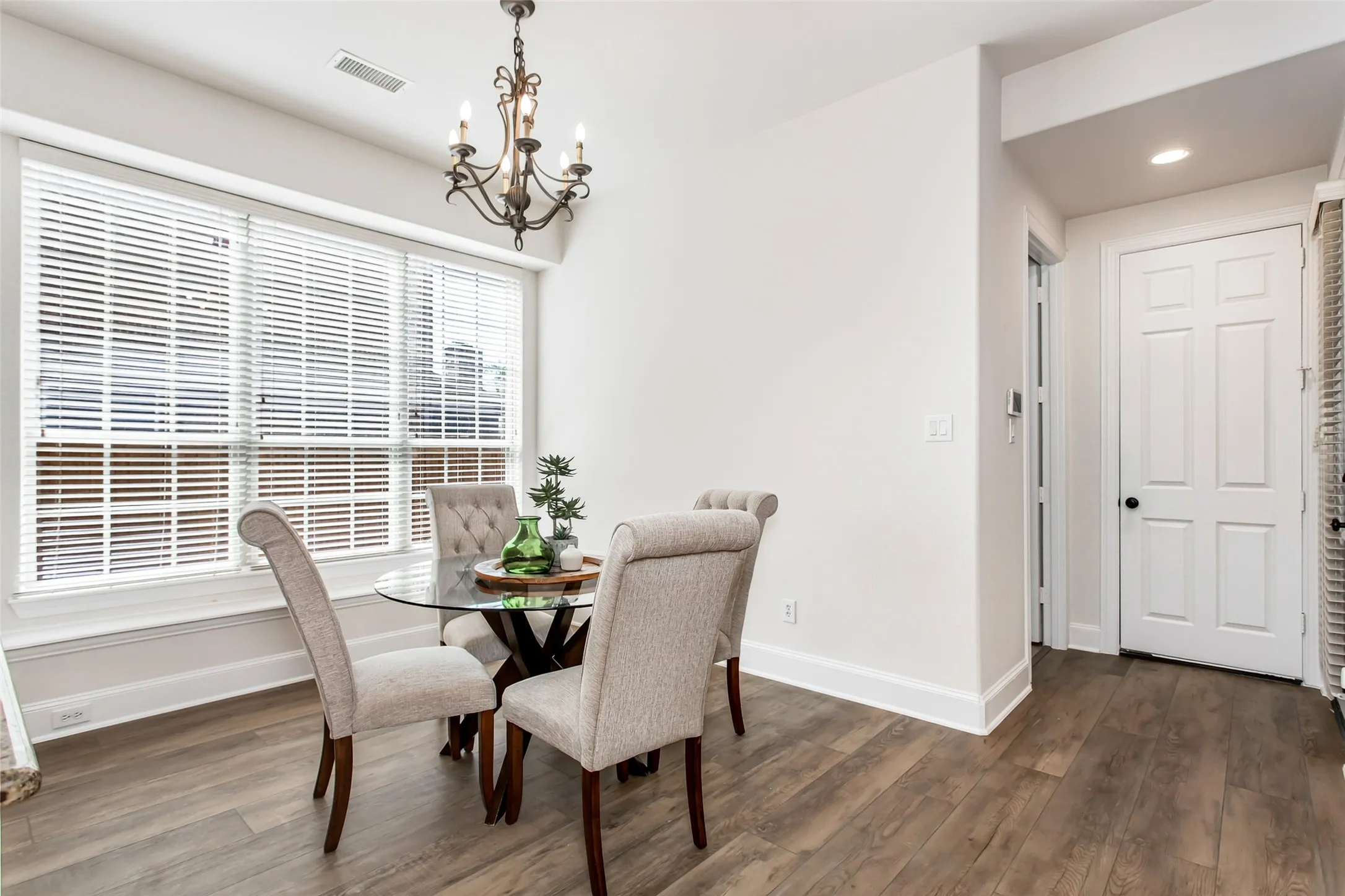 Wood-finish flooring, white trim, and a decorative chandelier