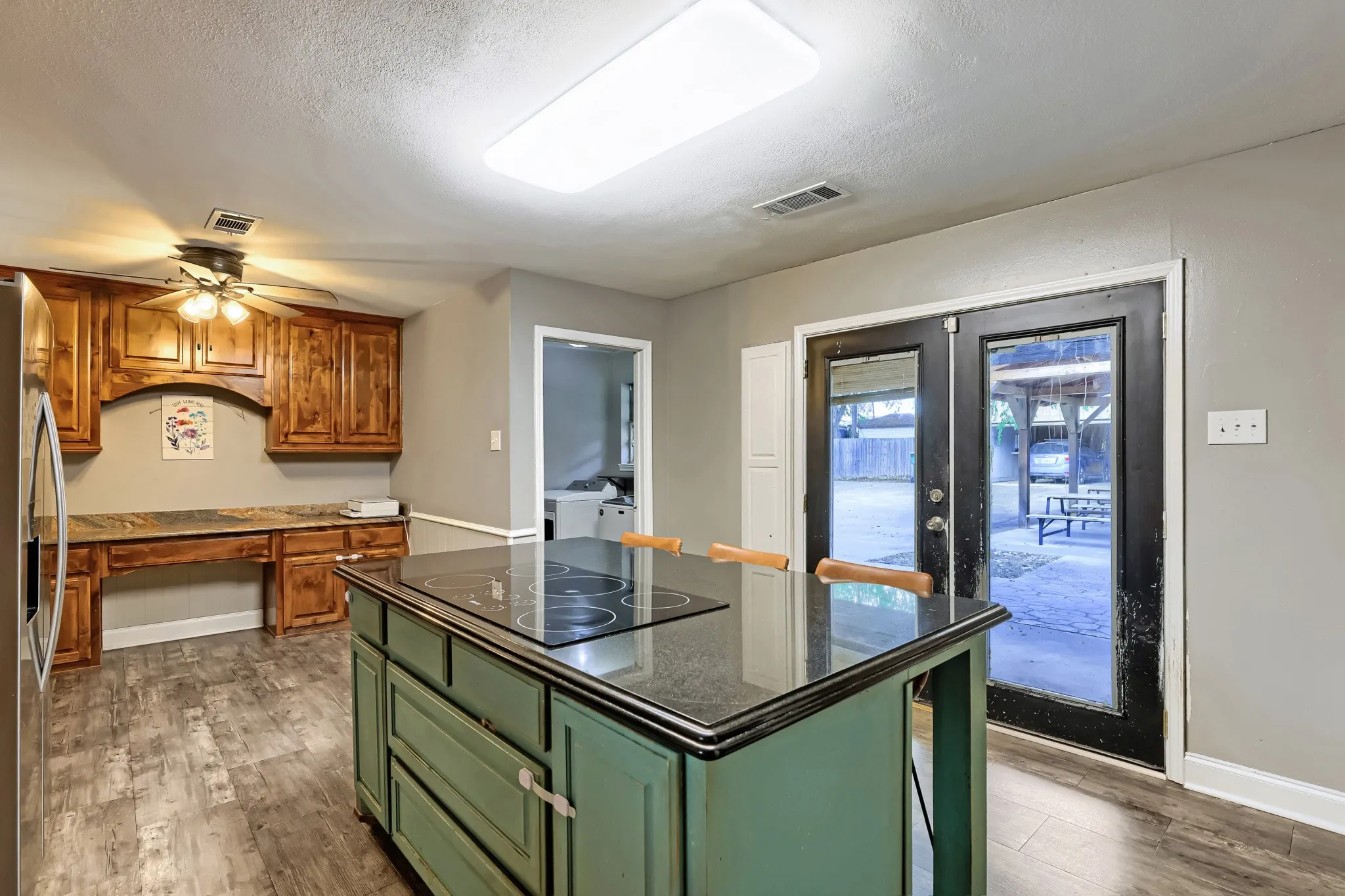 Kitchen featuring wood-finish flooring, a built-in cooktop, an island with storage, and double glass-paneled doors