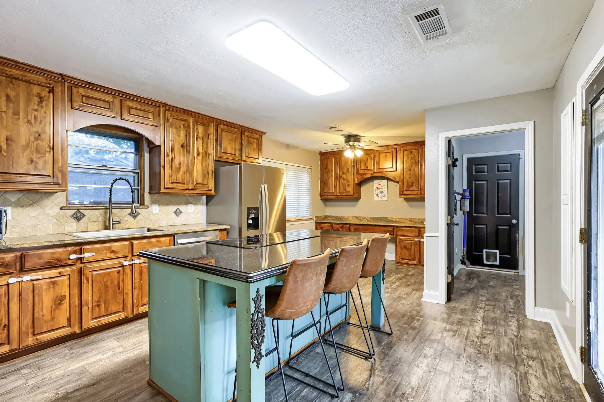 Kitchen featuring wood-finish cabinetry, a central island with a contrasting base, a tile backsplash, and stainless steel appliances