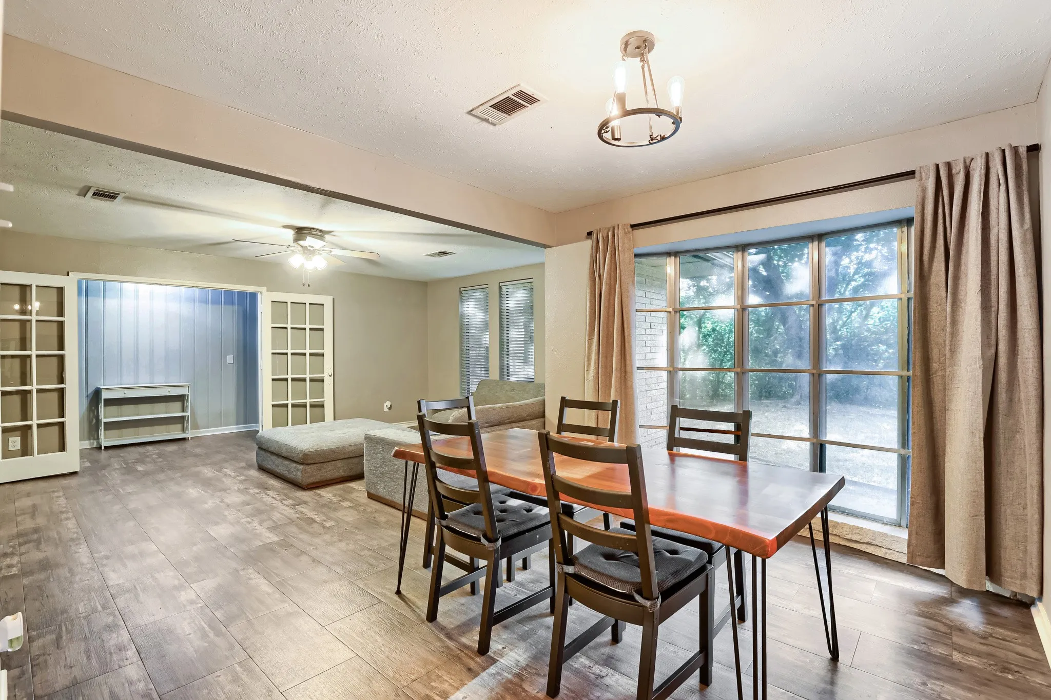 Expansive room featuring wood-finish flooring, a large multi-pane window, and a ceiling fan