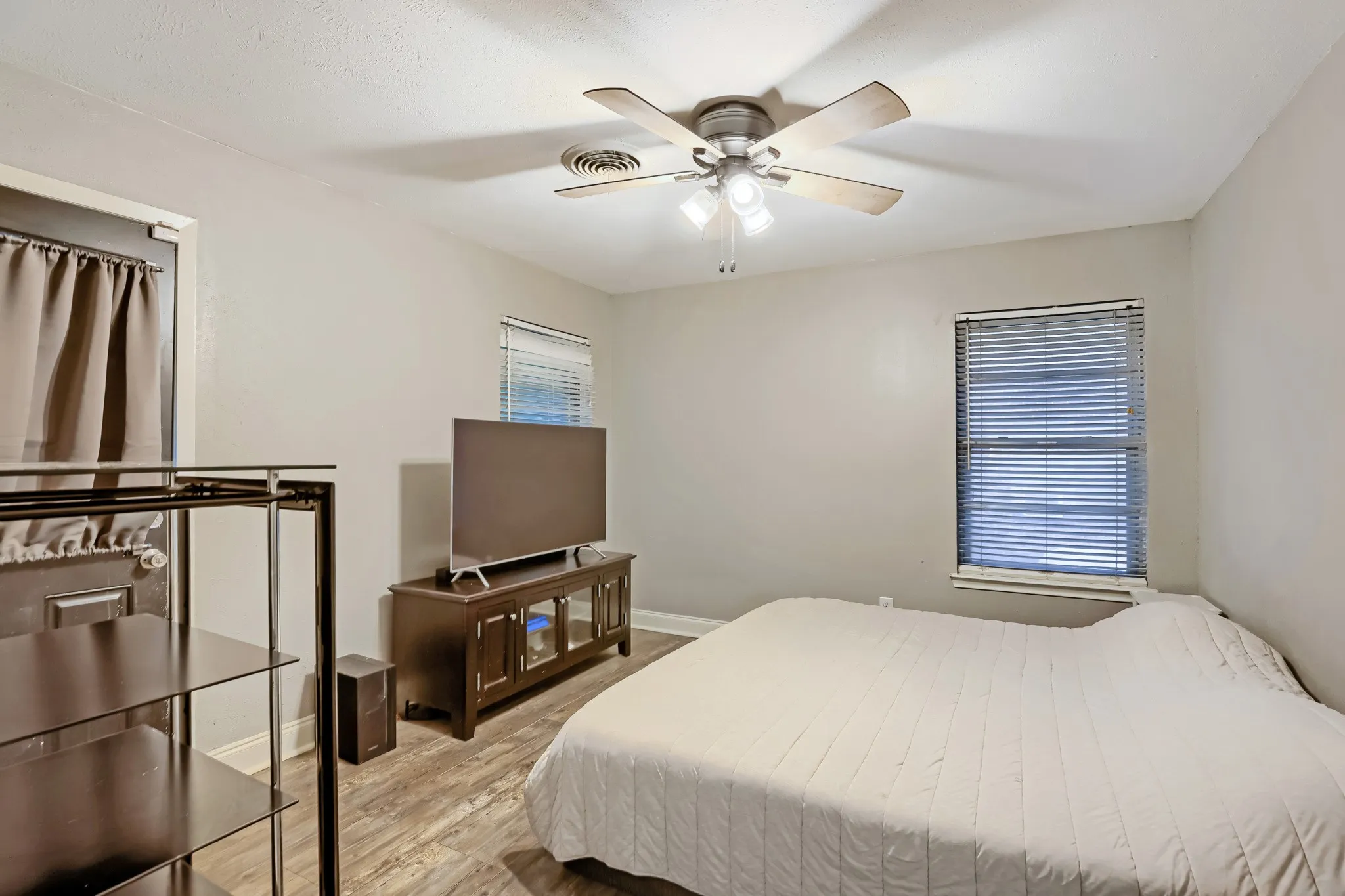 Neutral wall paint, wood-finish flooring, ceiling fan with integrated lighting, and window with blinds