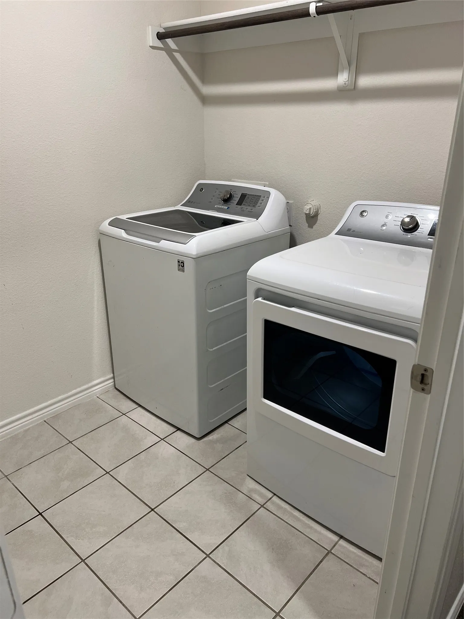 Clothes washing area featuring washer and dryer and light tile flooring