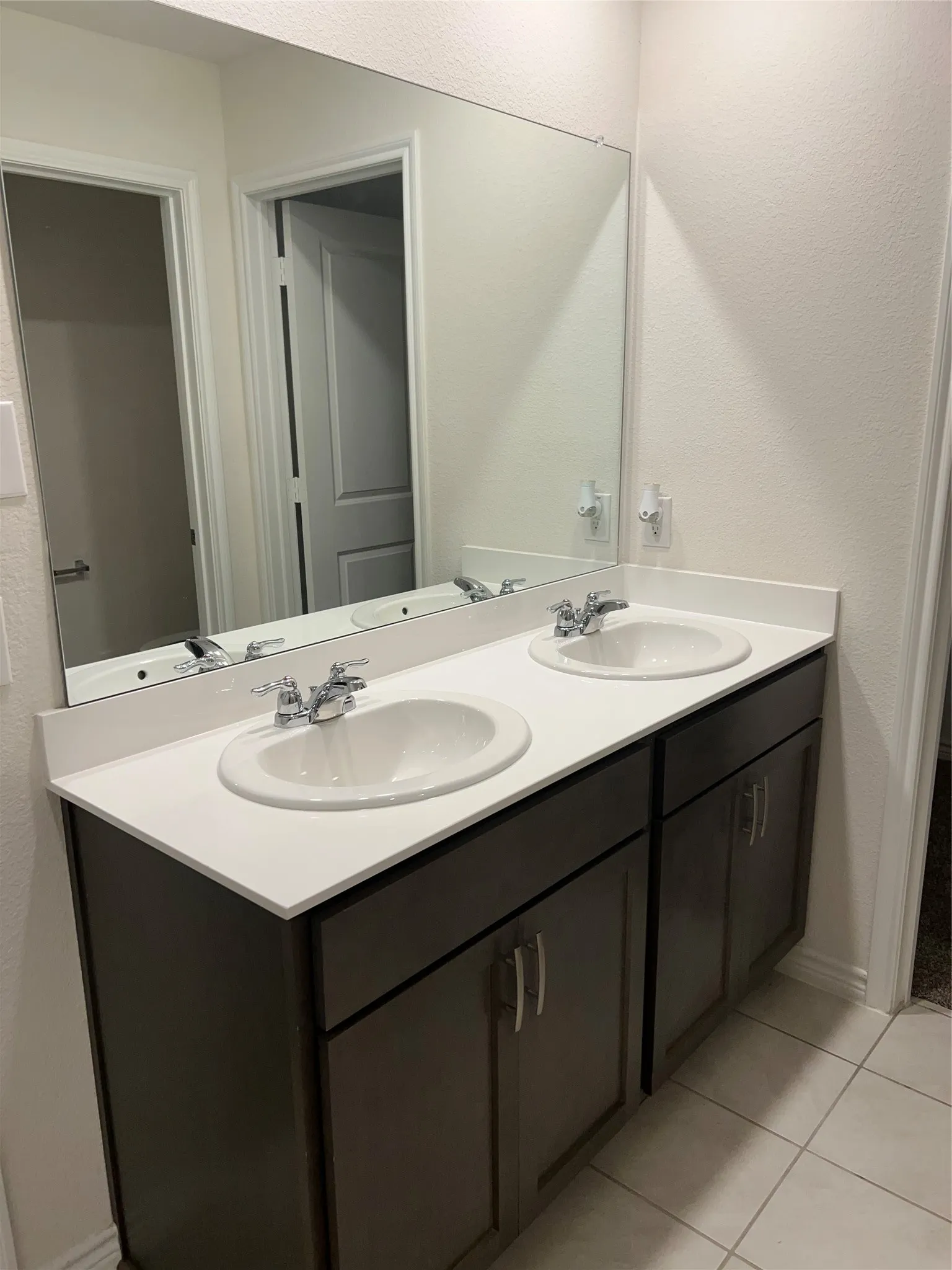 Bathroom featuring tile floors, oversized vanity, and dual sinks