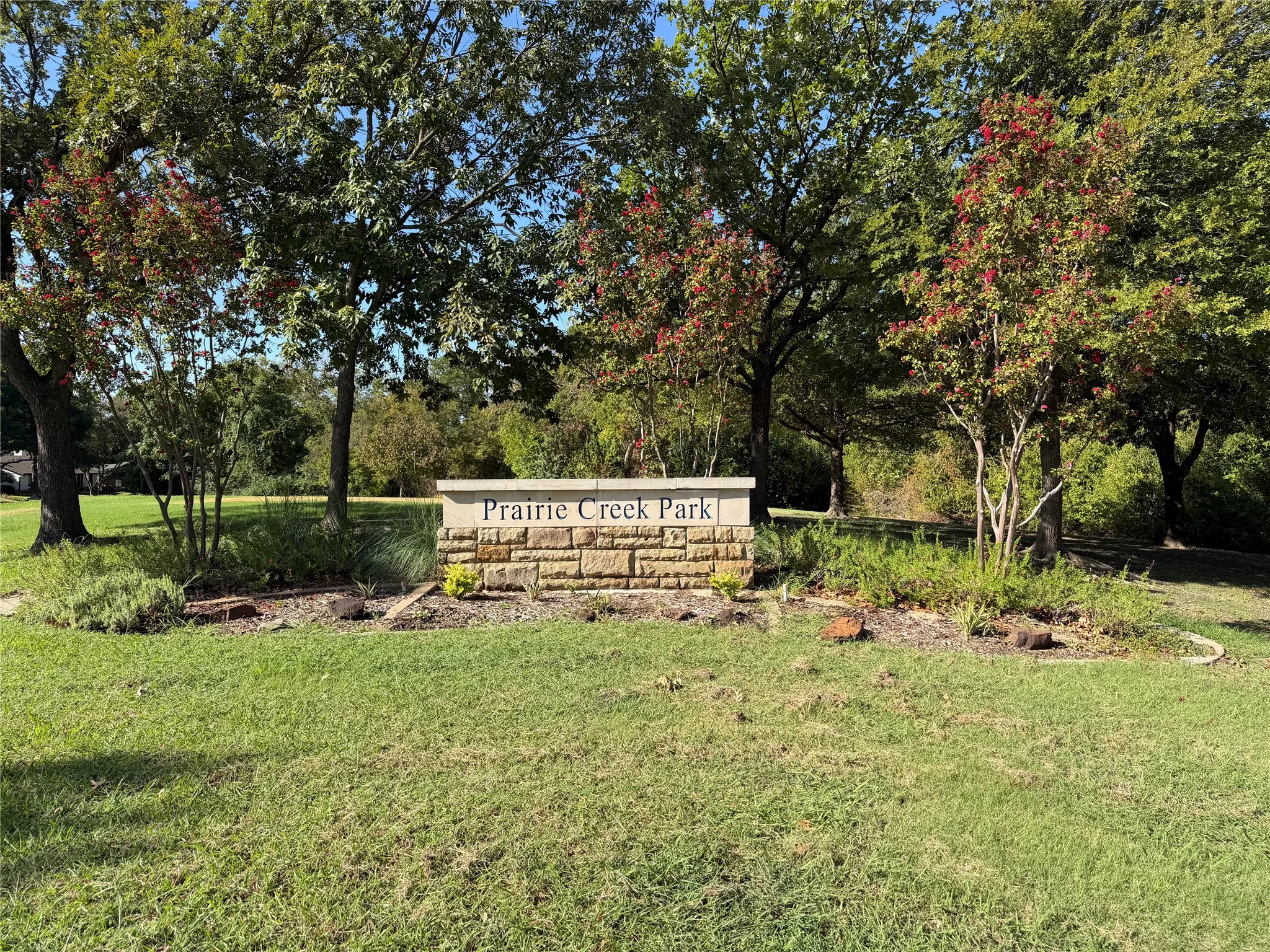 Prairie Creek Park stone monument surrounded by mature trees and expansive lawn