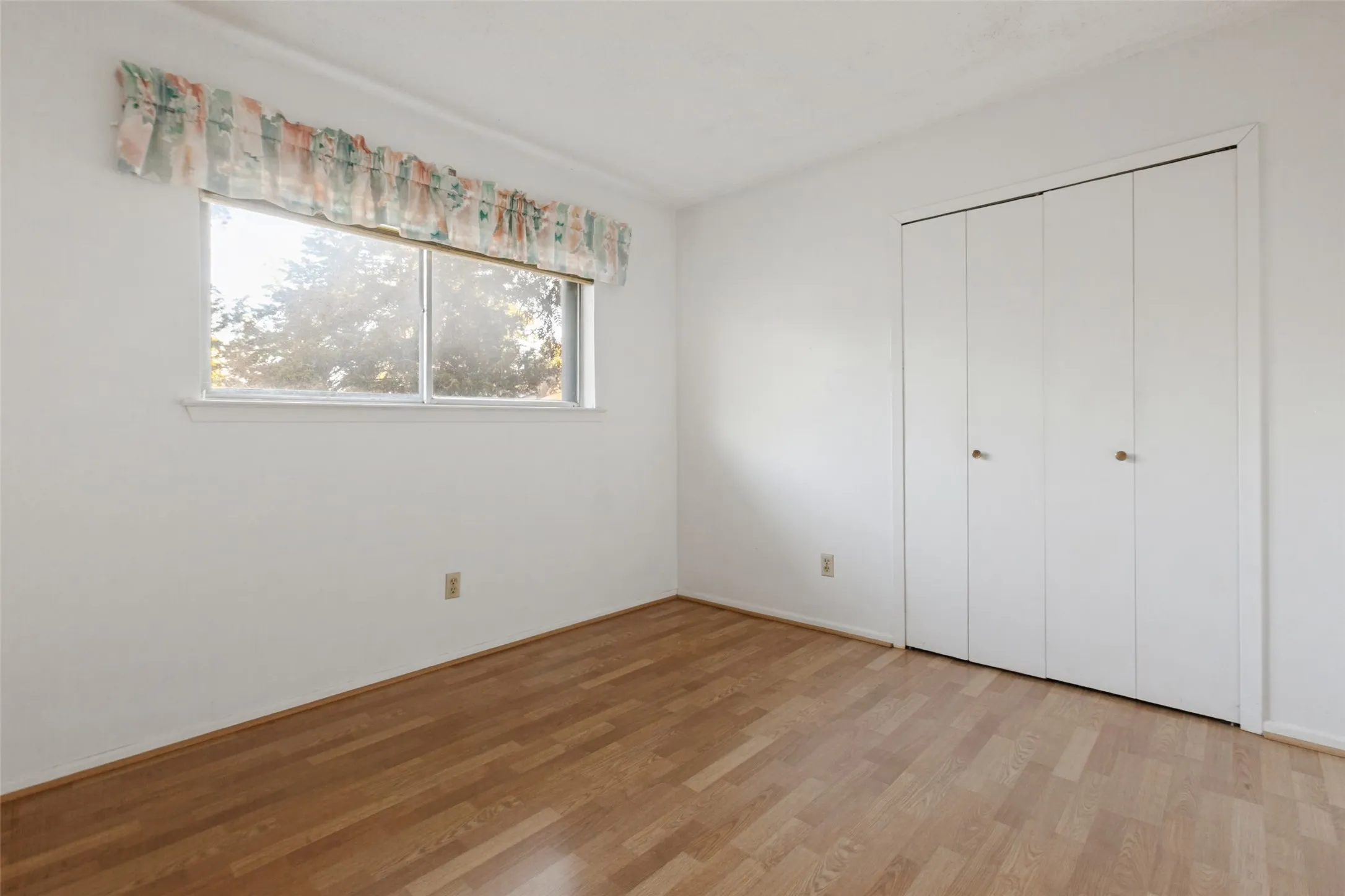 Wood-finish flooring, white walls, and a window with exterior visibility