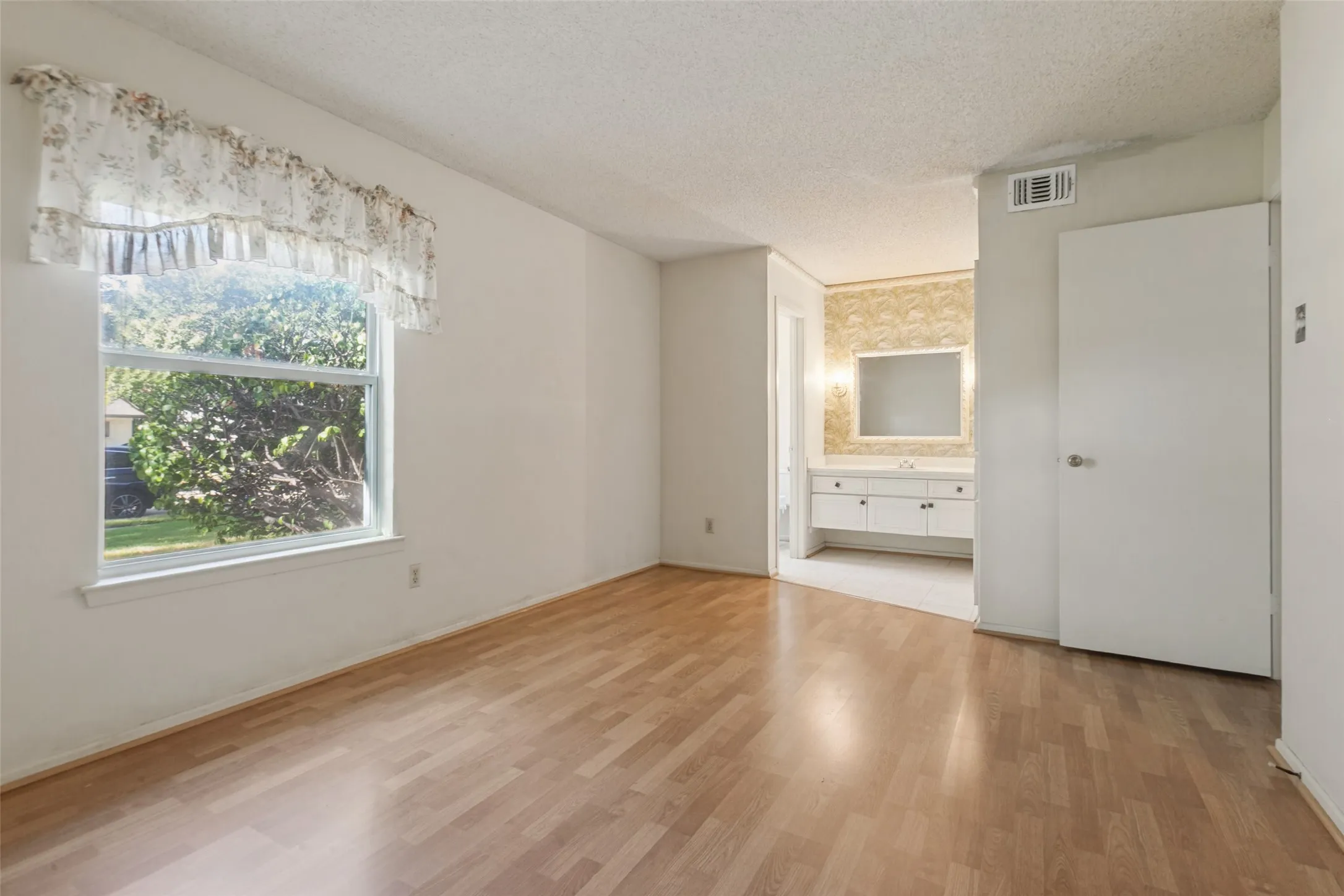 Wood-finish flooring, white walls, and a window providing natural light