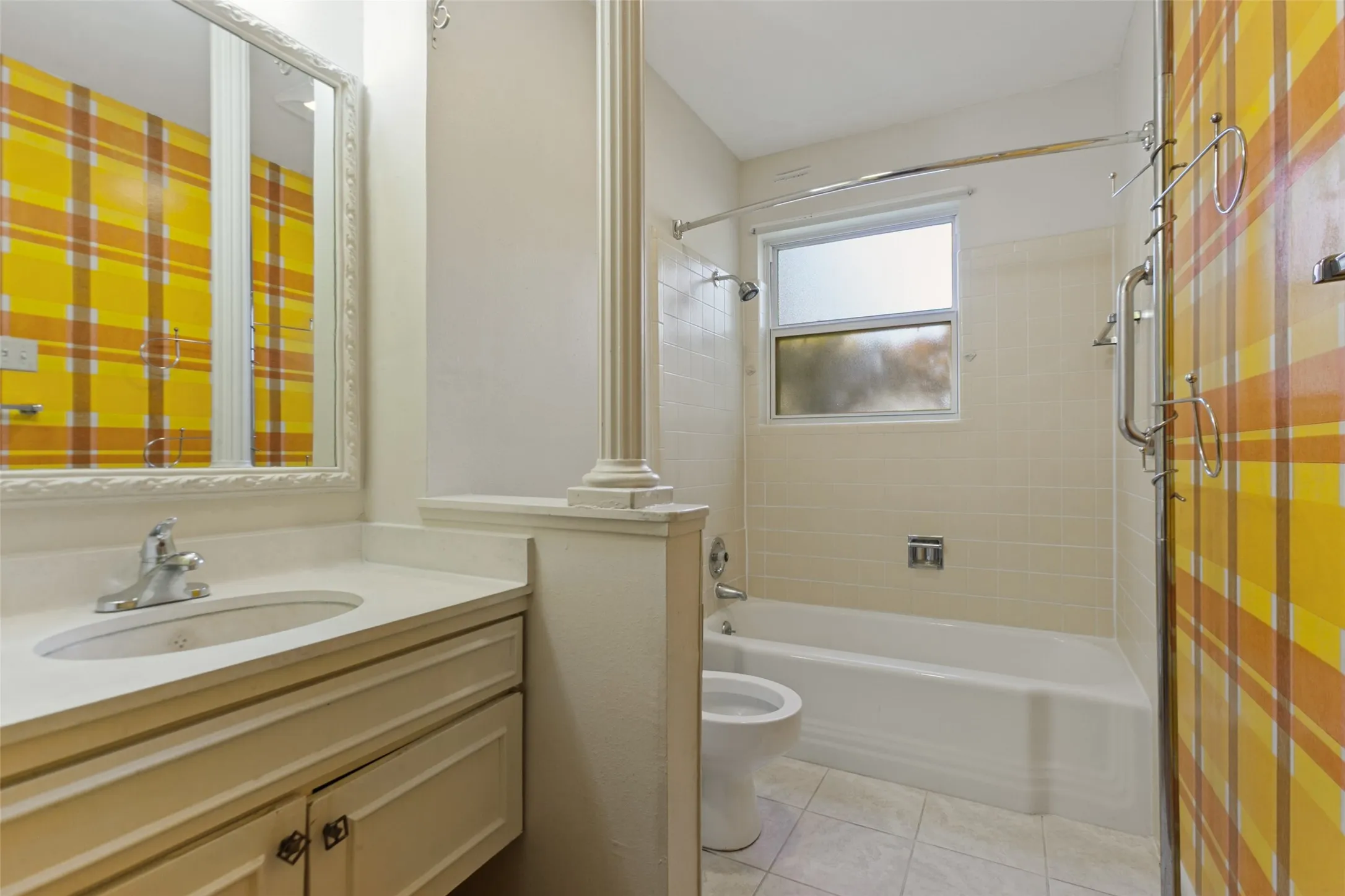 Pedestal column accent, vanity with integrated sink, framed mirror, and a bathtub with shower